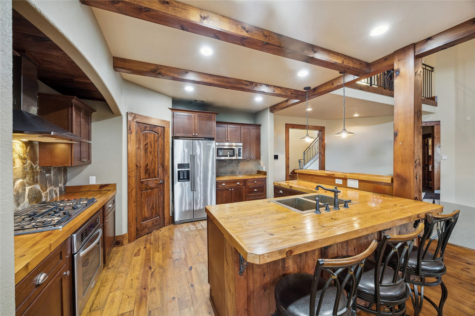 A large butcher-block island anchors this kitchen, offering abundant prep space and bar-style seating. Surrounded by stainless steel appliances, stone backsplash, and natural wood details, the kitchen is both timeless and totally functional. Virtually decluttered to help visualize potential use.