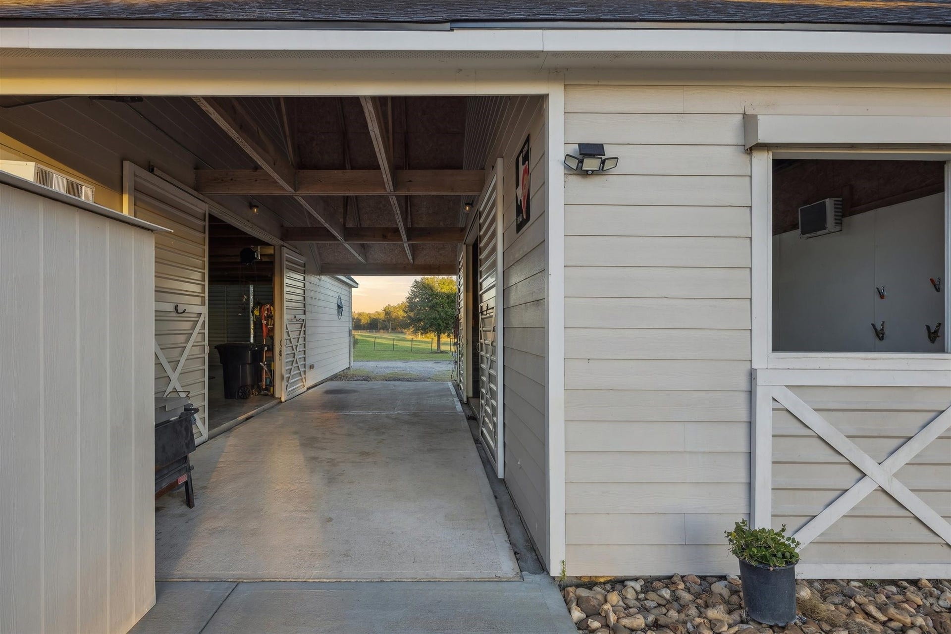 The well-kept stable features a wide breezeway connecting multiple stalls and storage areas. With durable concrete flooring, high exposed rafters, and tidy white siding, the space is both practical and polished perfectly suited for daily equestrian routines.