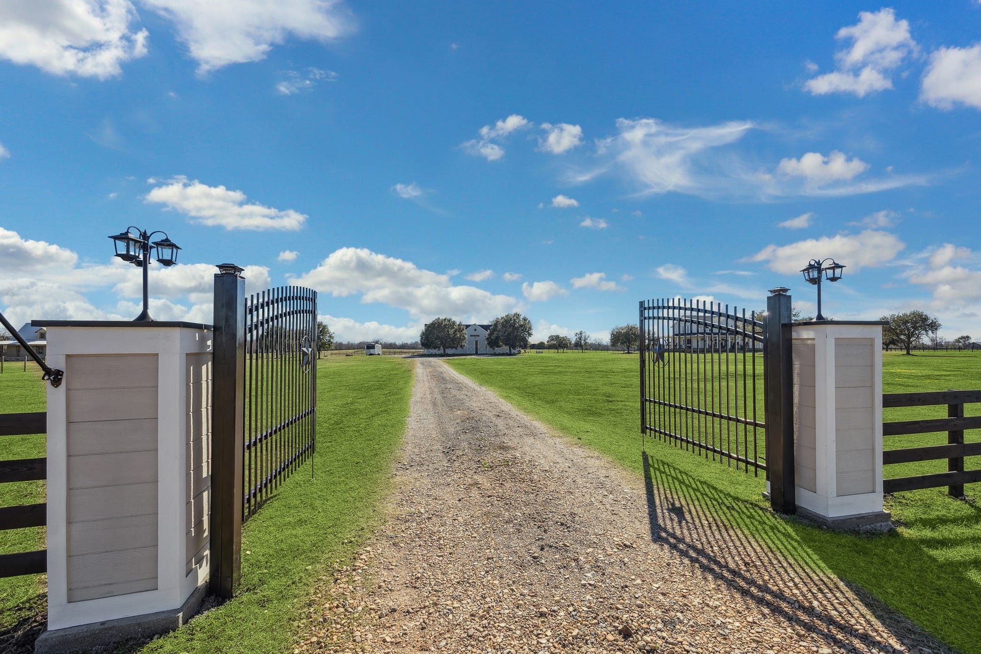 A grand Texas welcome this gated entry sets the tone for your private ranch estate. The dual iron gates, flanked by lantern-lit pillars, open to a long gravel drive lined with lush green pasture, leading to the heart of this  nearly 19-acre equestrian property. Security and style meet in a setting where the land holds a wildlife exemption, reflecting its purpose, care, and connection to nature.