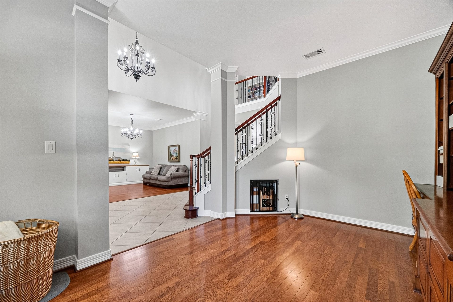 3102 Purple Finch, Missouri City, TX 77459 Bright, elegant entryway with hardwood floors and a stylish staircase. The space opens into a living area with tiled flooring and decorative chandeliers.
