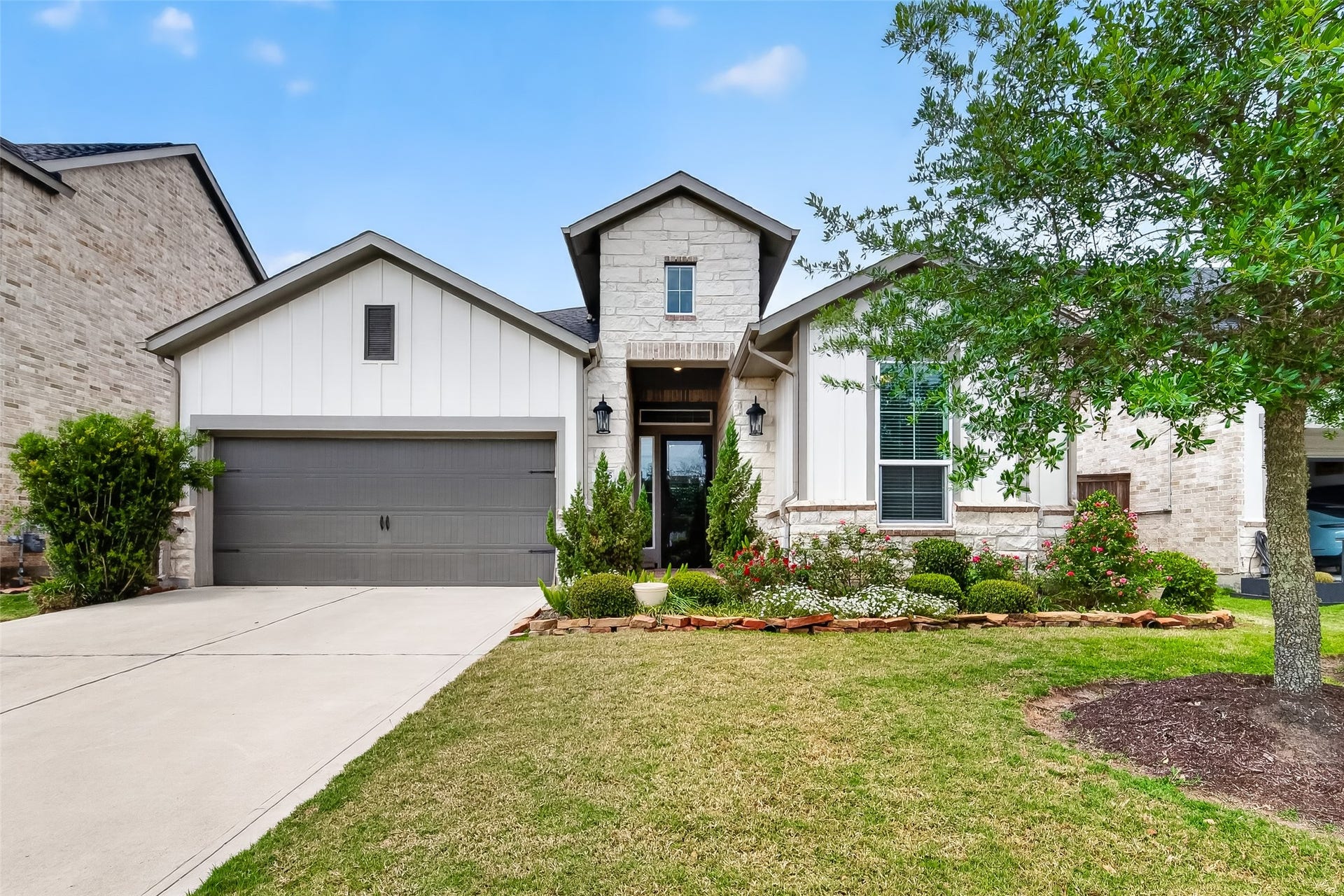 3415 Mckinney Ridge Drive, Houston, TX 77059 Charming single-story patio home with a modern exterior, featuring a combination of stone and siding. It has a well-maintained front yard with native plants, a spacious driveway, and a two-car garage.