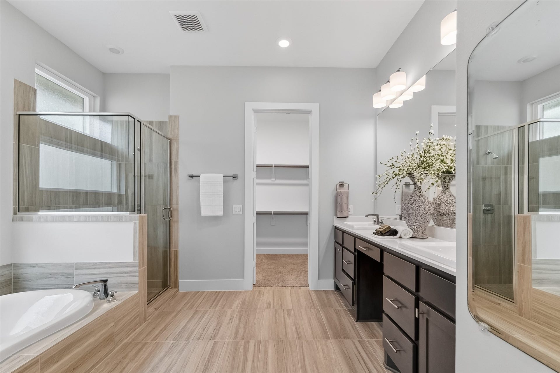 3415 Mckinney Ridge Drive, Houston, TX 77059 The primary bath has a glass-enclosed shower and a separate soaking tub. This area includes a double vanity with ample storage, sleek fixtures, and stylish lighting. The neutral color palette and large mirror enhance the bright, airy feel, and there's direct access to a walk-in closet.