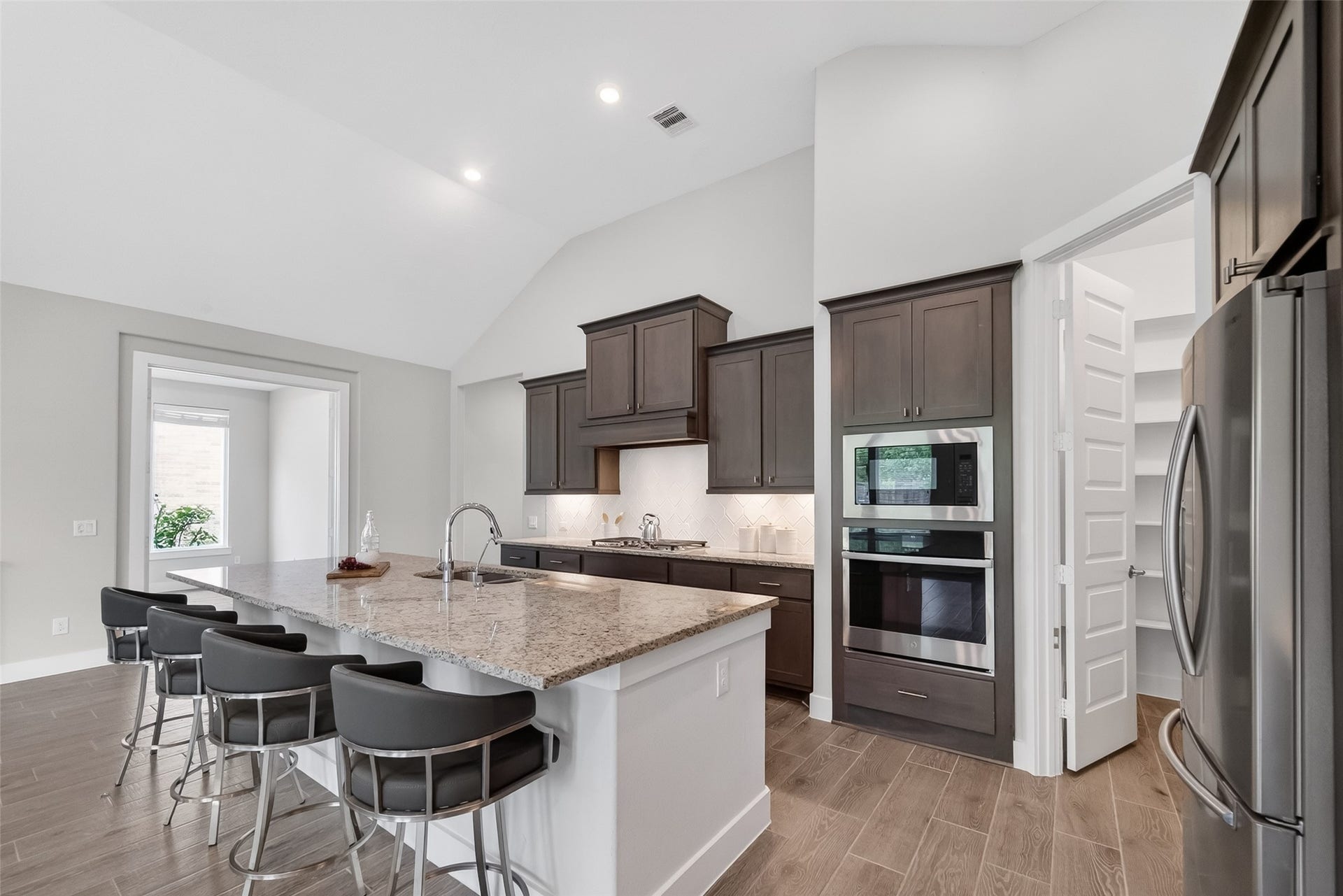 3415 Mckinney Ridge Drive, Houston, TX 77059 3415 McKinney Ridge -Beautiful kitchen features sleek dark cabinetry, a huge island with seating, stainless steel appliances, and ample natural light from an adjacent open area.