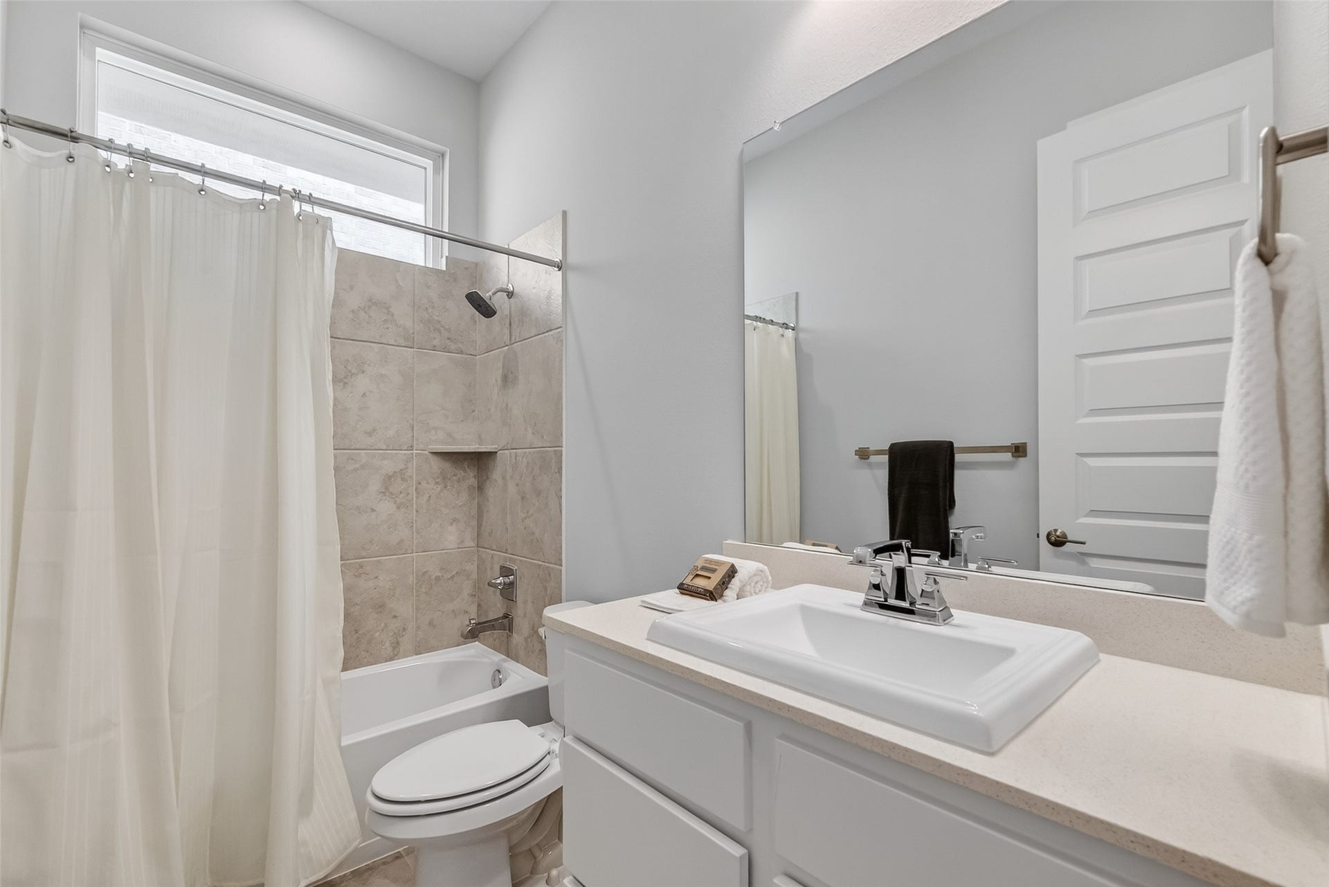 3415 Mckinney Ridge Drive, Houston, TX 77059 This bathroom features a clean, modern design with a tiled shower-tub combo, a large mirror, and a sleek vanity with ample counter space.