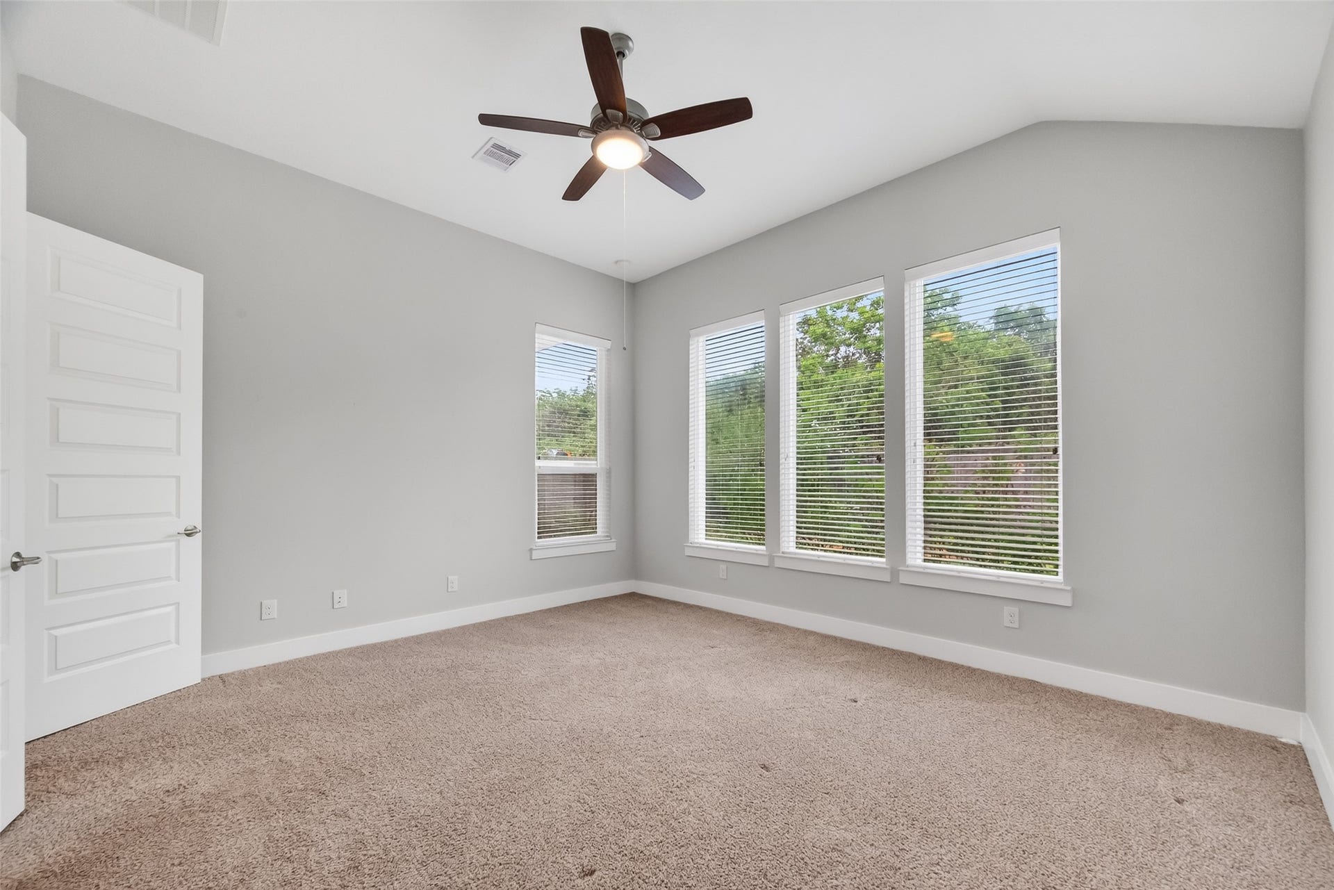 3415 Mckinney Ridge Drive, Houston, TX 77059 Primary bedroom with neutral walls & large windows offering natural light, carpeted flooring, and a ceiling fan. Relaxing view of the backyard gardens.