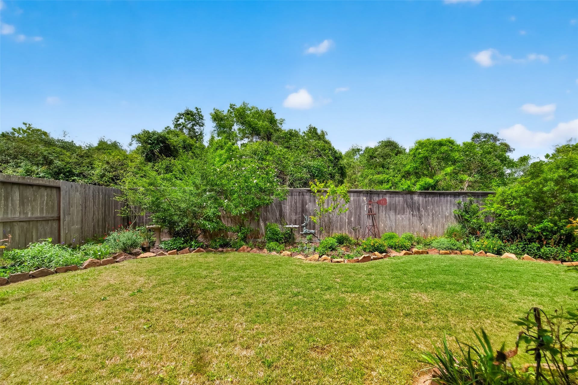 3415 Mckinney Ridge Drive, Houston, TX 77059 Private backyard has a well-manicured lawn, bordered by a wooden fence and lush greenery, offering a serene outdoor space.