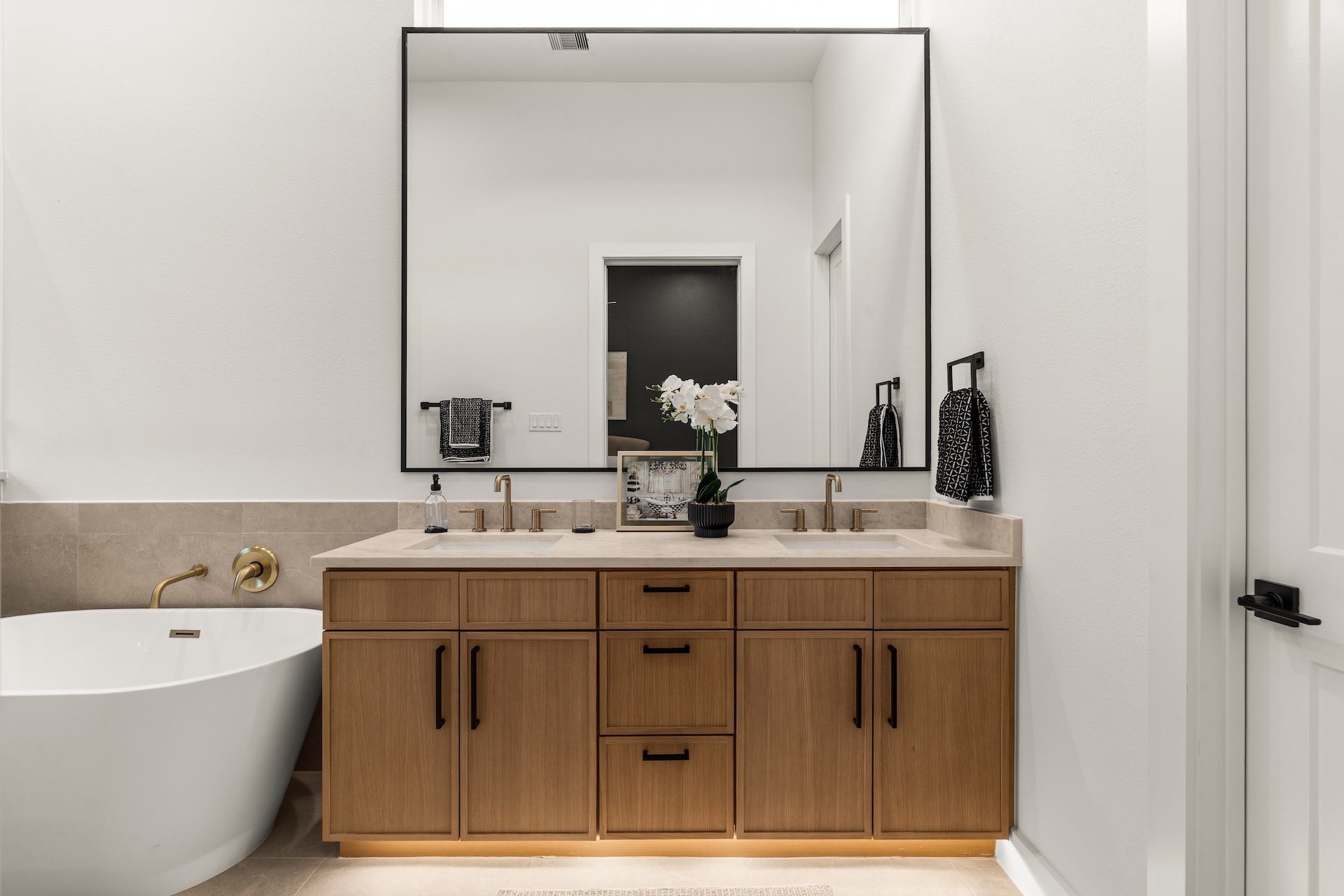 6619 Avenue Q, #A/B, Houston, TX 77011 Spa-inspired primary vanity featuring dual undermount sinks, ambient toe-kick lighting, and custom warm wood cabinetry.