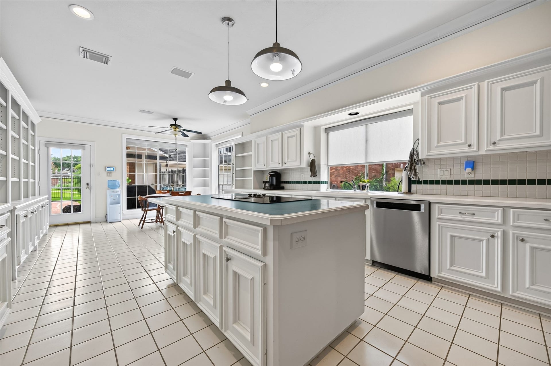 18 Tredington Street, Sugar Land, TX 77479 Spacious kitchen with white cabinetry, a large island, and modern appliances, featuring ample natural light from large windows and a door leading to the outdoor area.