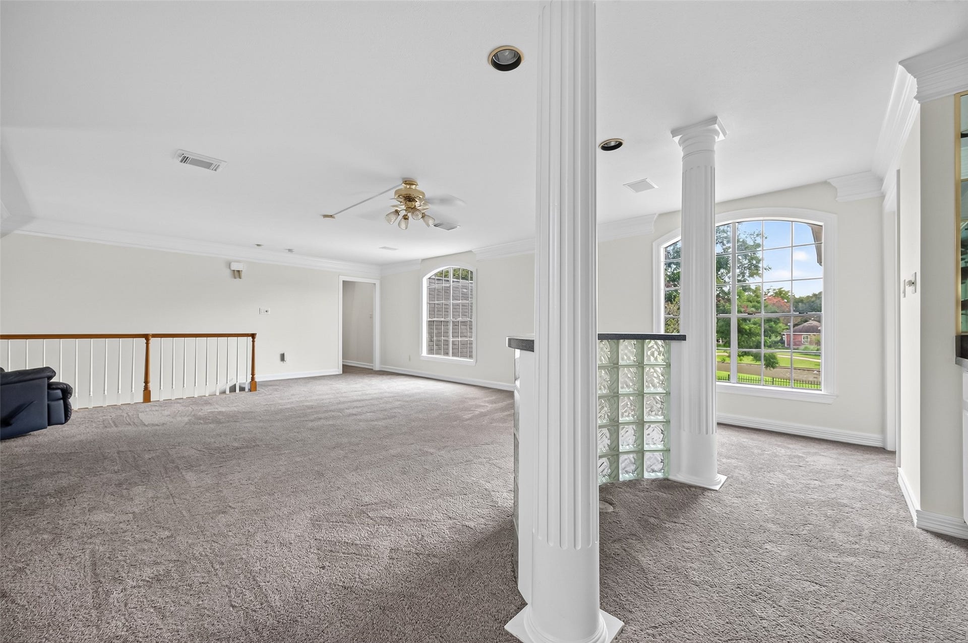 18 Tredington Street, Sugar Land, TX 77479 Another view of the spacious and bright living area featuring large windows, elegant columns, and carpeting, perfect for relaxation and entertainment.