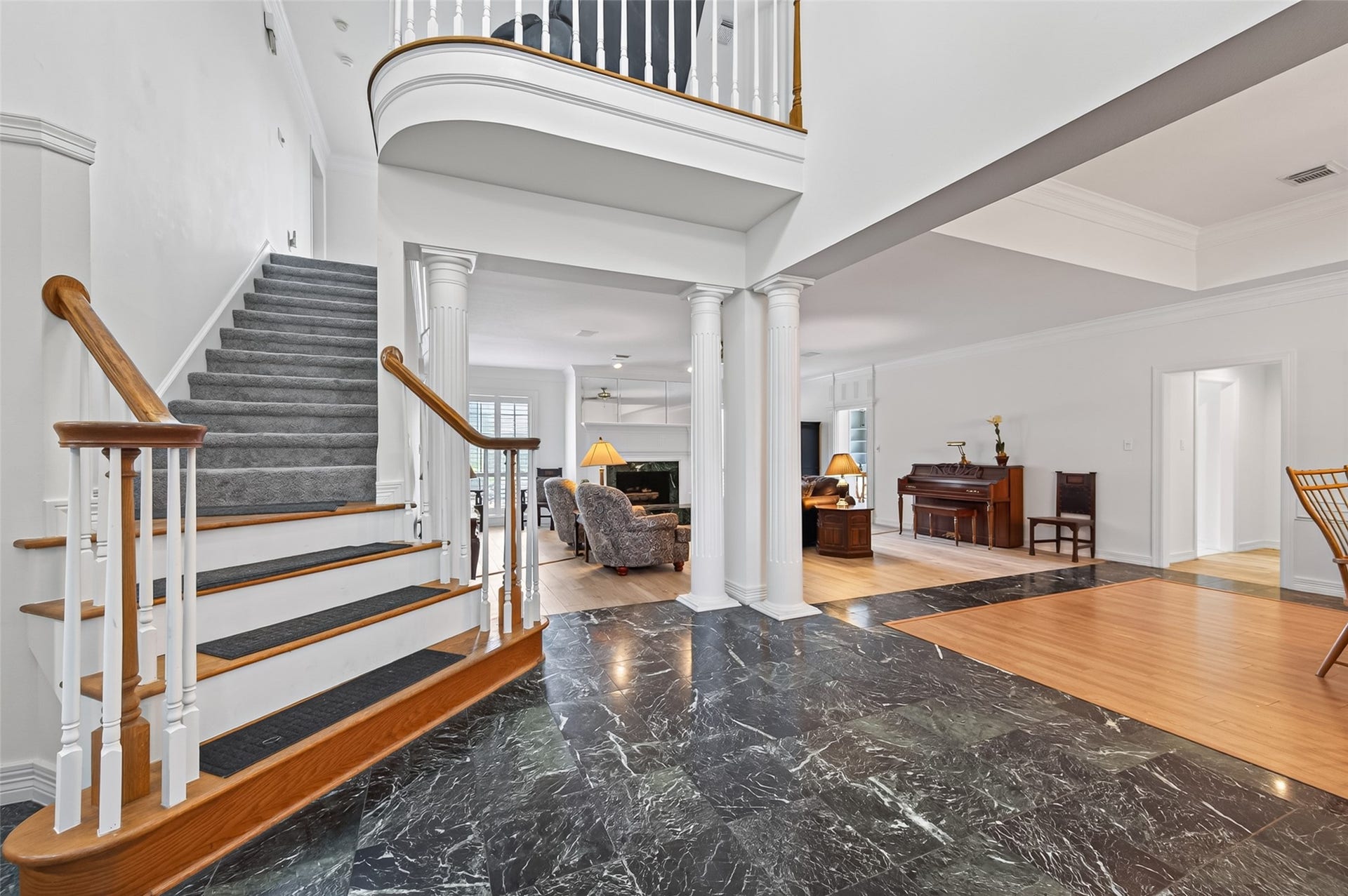 18 Tredington Street, Sugar Land, TX 77479 Elegant entryway featuring a grand staircase with custom flooring and classic columns, seamlessly leading into a spacious living area.