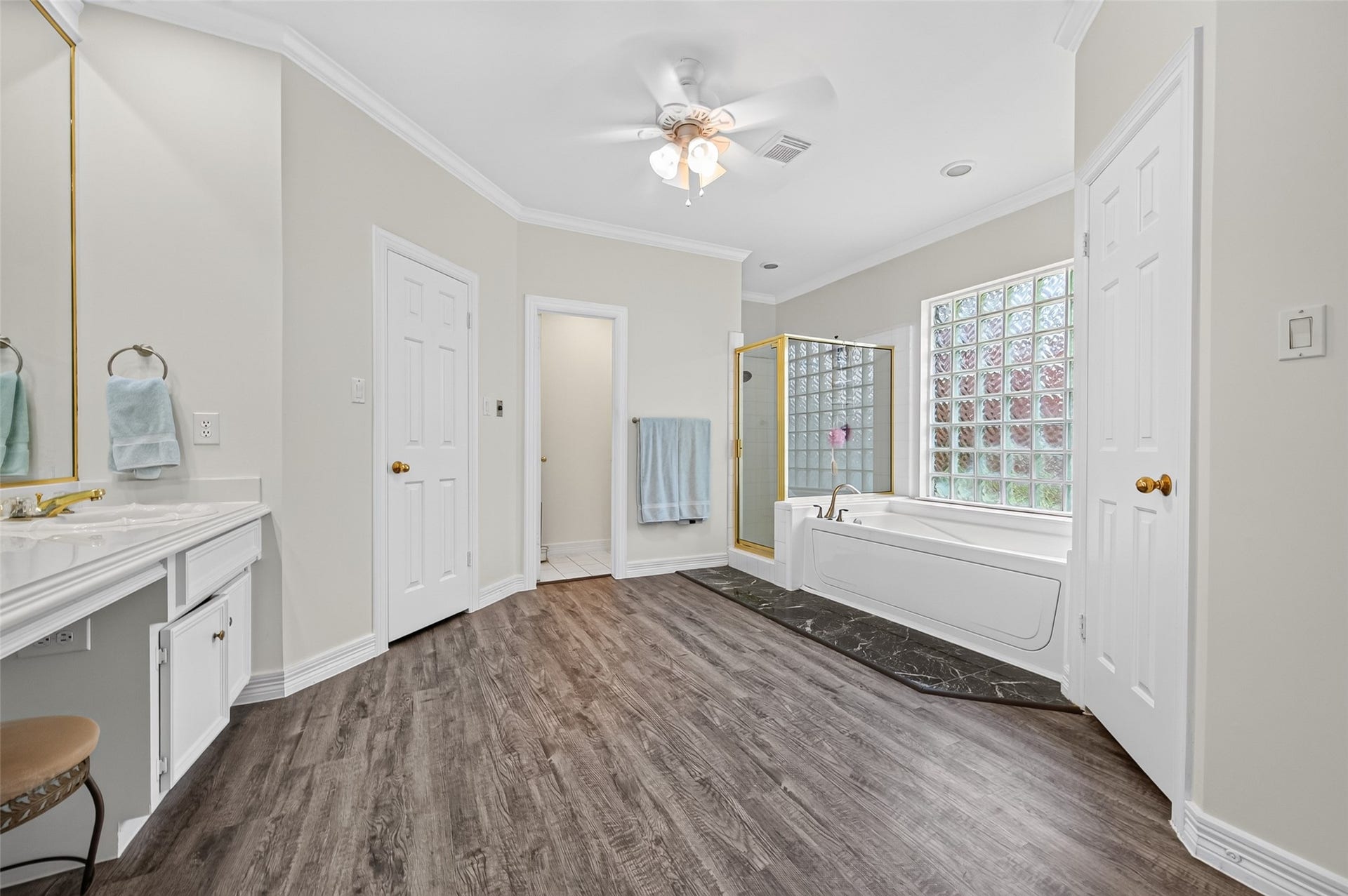 18 Tredington Street, Sugar Land, TX 77479 Spacious bathroom featuring elegant flooring, a luxurious soaking tub with a glass block window, separate shower, and a dual vanity with ample storage.