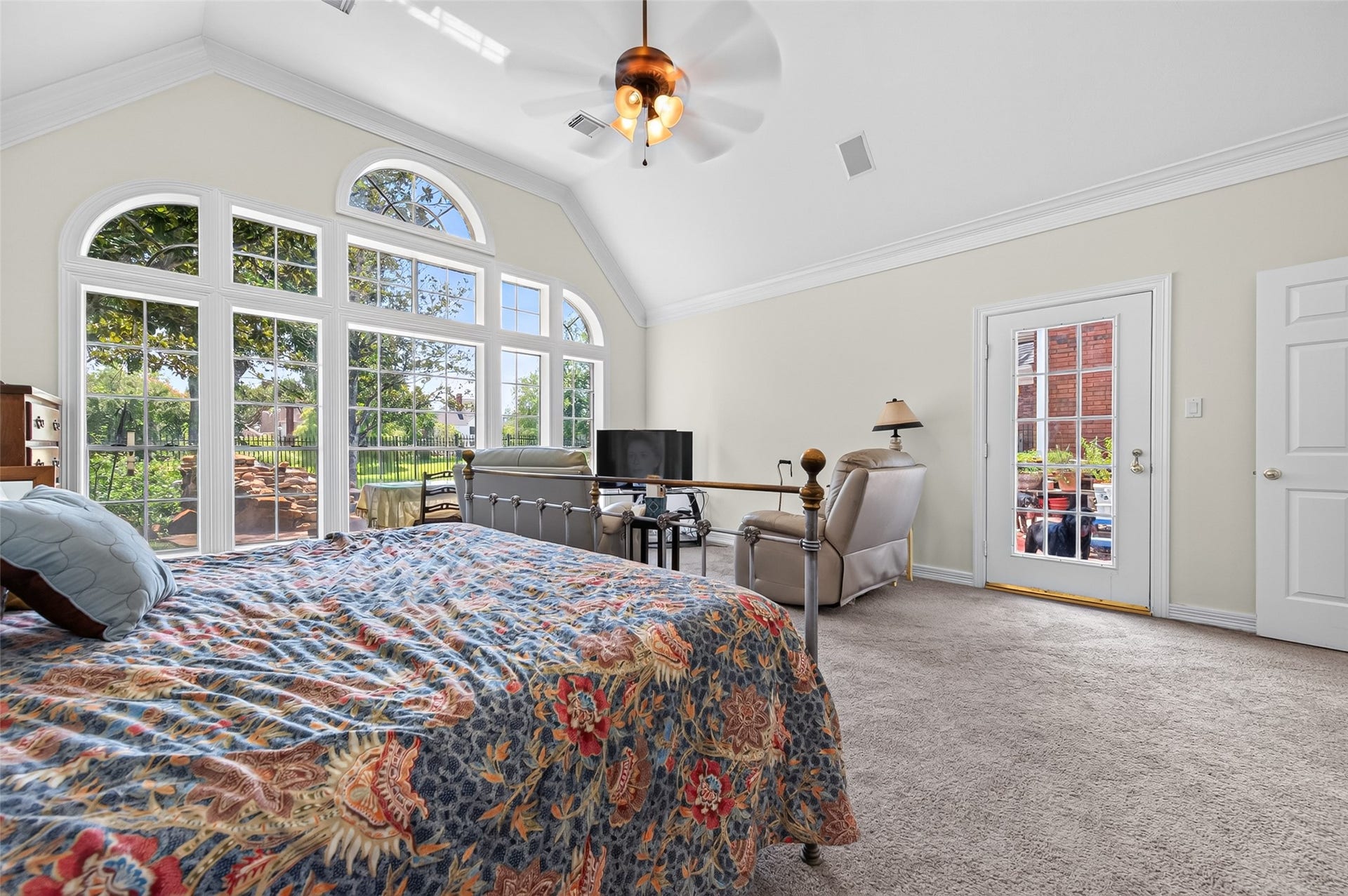 18 Tredington Street, Sugar Land, TX 77479 Expansive primary bedroom with vaulted ceilings and abundant natural light from beautiful large arched windows, offering a serene view of the backyard oasis and its own private access.