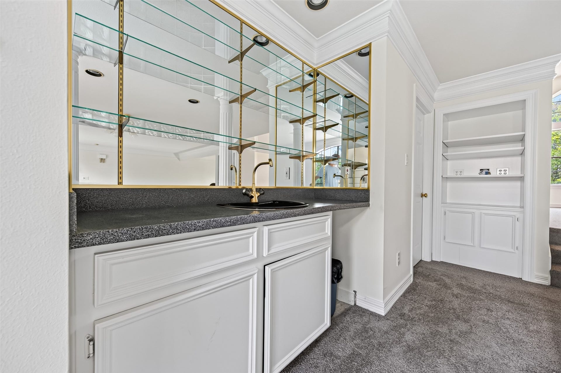 18 Tredington Street, Sugar Land, TX 77479 Elegant wet bar area featuring sleek countertops, glass shelving, and ample cabinetry, perfect for entertaining or additional storage.