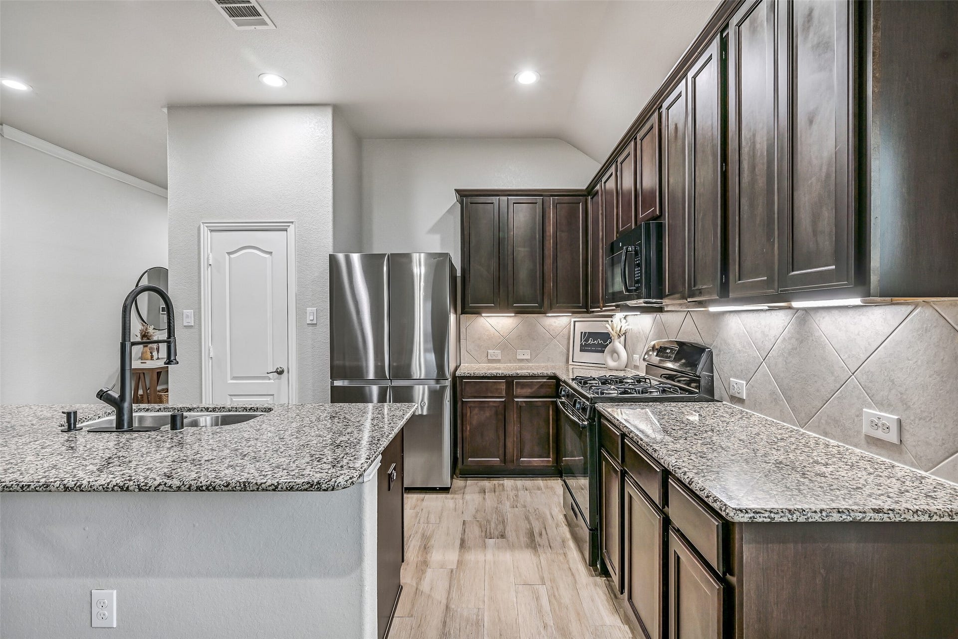 A generous granite island with undermount sink anchors the kitchen, providing abundant prep space while keeping the cook connected to both the breakfast area and family room. Storage is plentiful thanks to extensive upper and lower cabinetry.
