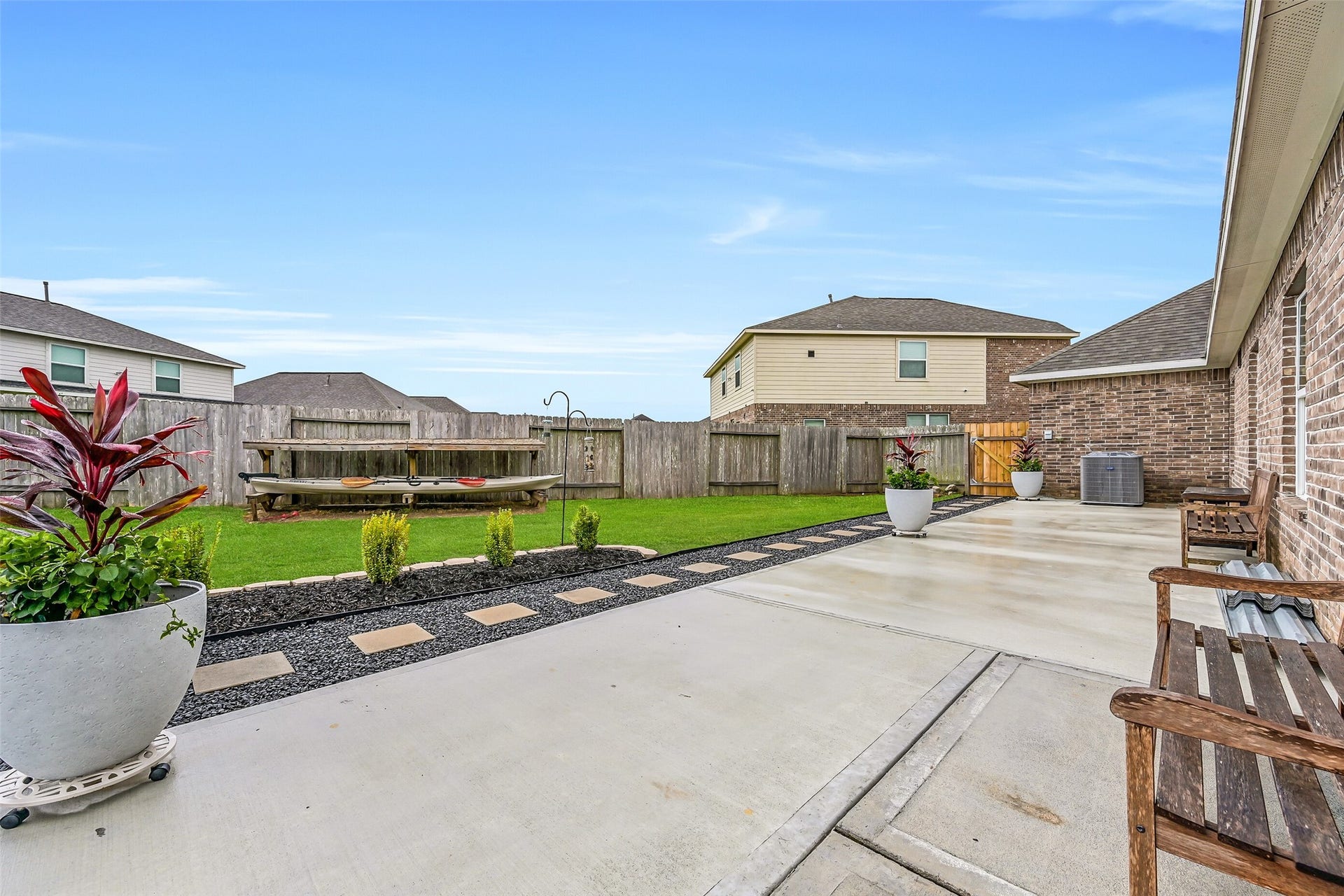 Beyond the covered patio, an oversized concrete entertaining area provides even more room for outdoor dining, grilling, and gathering with friends. Attractive landscaping, stepping stone pathways, and the expansive backyard create a space that's as functional as it is inviting.