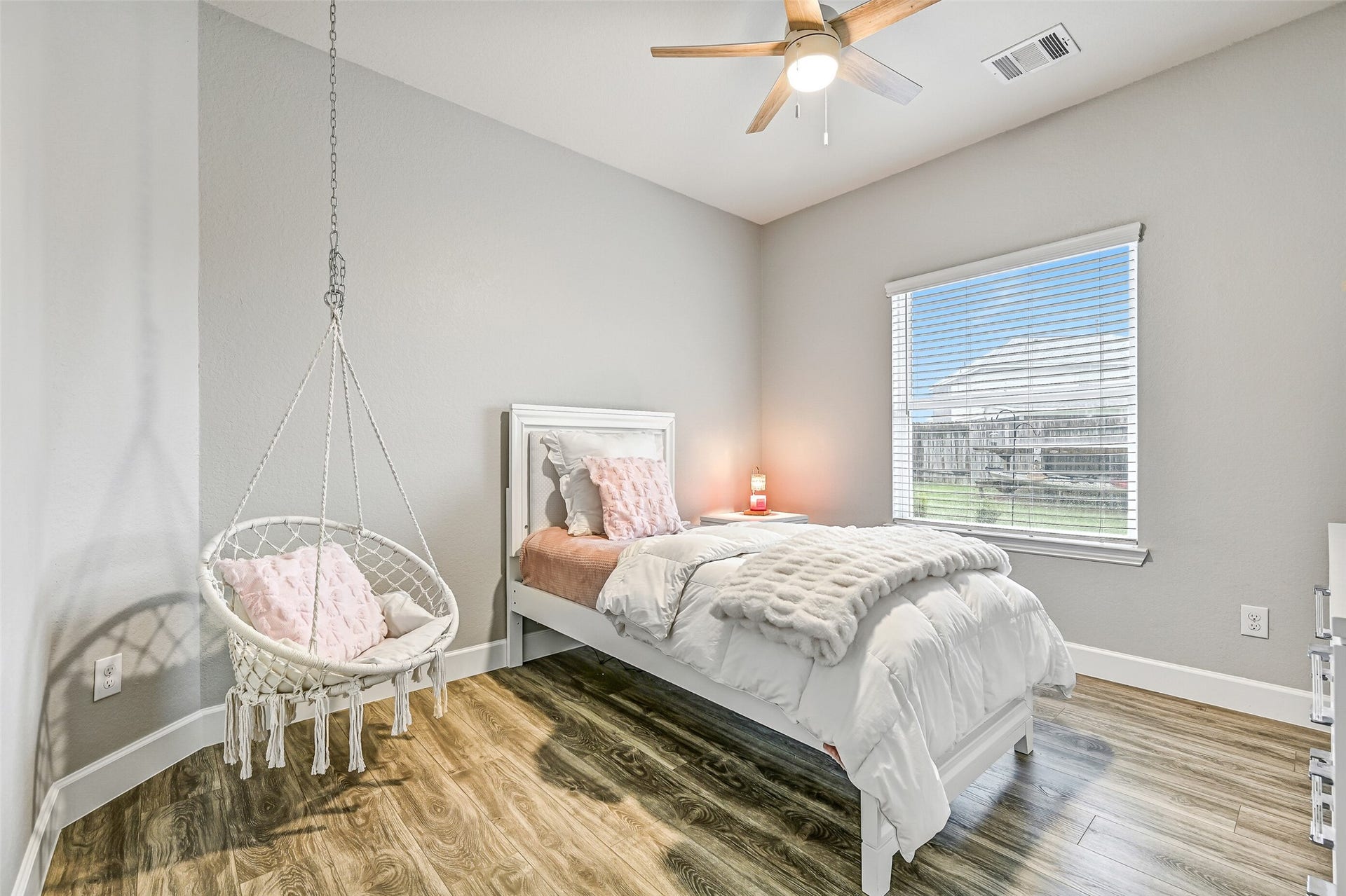 One of two secondary bedrooms is generously sized with tall ceilings, a ceiling fan, durable flooring, and abundant natural light. This comfortable room is perfect for family, guests, or anyone needing flexible living space.