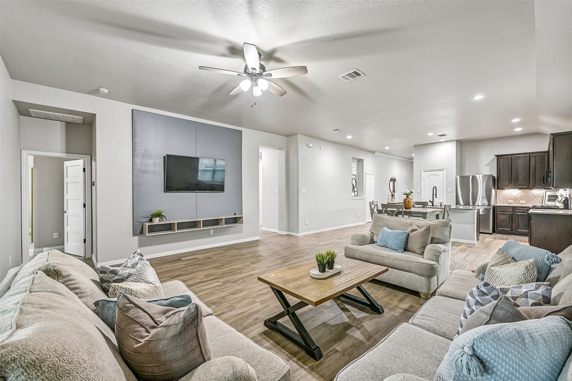 The expansive family room offers plenty of space for large furniture arrangements while maintaining an open connection to the kitchen. Recessed lighting, elevated ceilings, and durable wood-look tile flooring enhance the airy atmosphere.