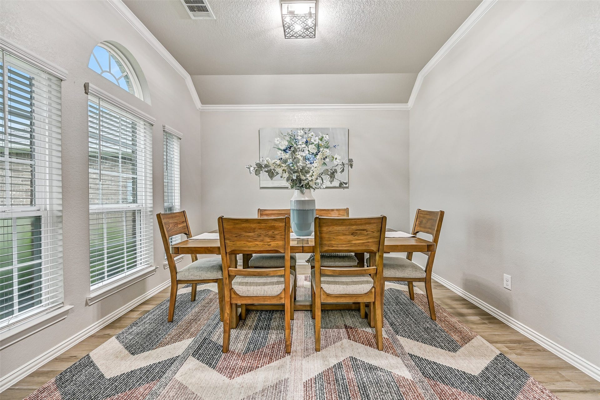 Just off the foyer, the formal dining room offers an elegant setting for family dinners and holiday gatherings. Elevated ceilings, crown molding, and oversized windows make this flexible space feel bright, open, and inviting.