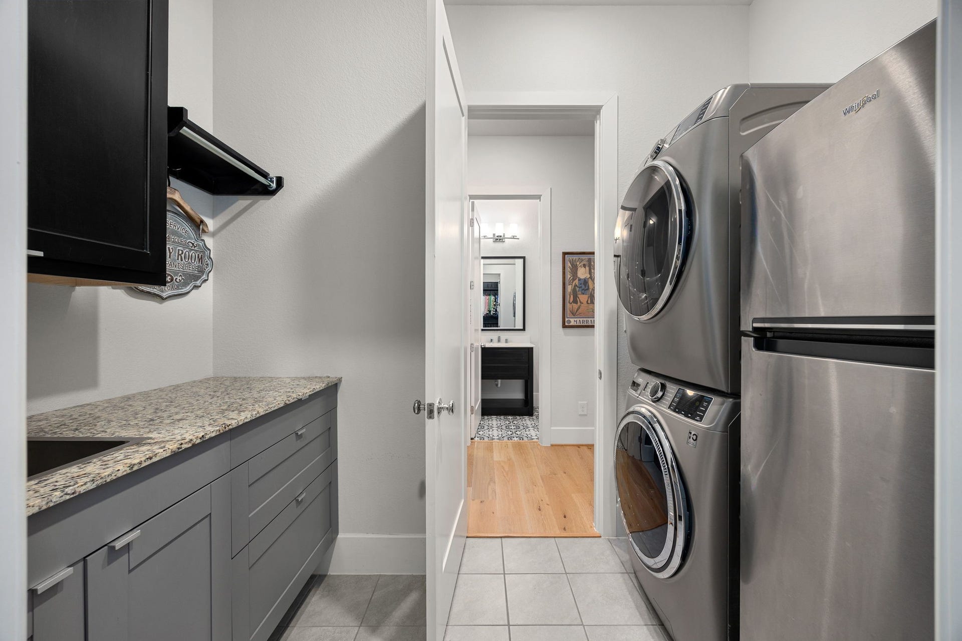 18 Gentle Branch Place, The Woodlands, TX 77375 Convenience at its finest in this spacious laundry room, complete with an included GE high-efficiency washer and dryer set with steam capabilities and refrigerator. This functional space also features a built-in utility sink, ample counter space for folding, and custom cabinetry for all your storage needs.