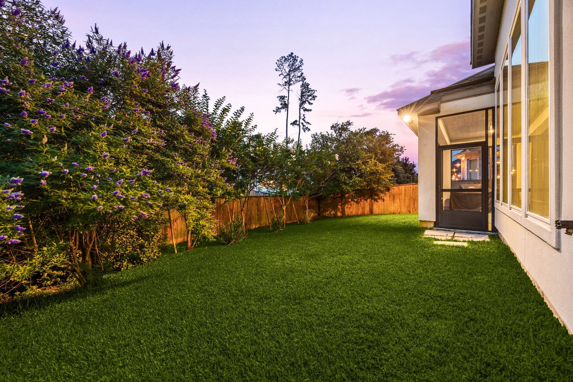 18 Gentle Branch Place, The Woodlands, TX 77375 Enjoy peace and privacy in this meticulously maintained backyard. The lush green lawn is bordered by a full privacy fence and mature greenery, offering a quiet escape. The expansive windows of the main living area provide a beautiful vantage point of this serene outdoor space.