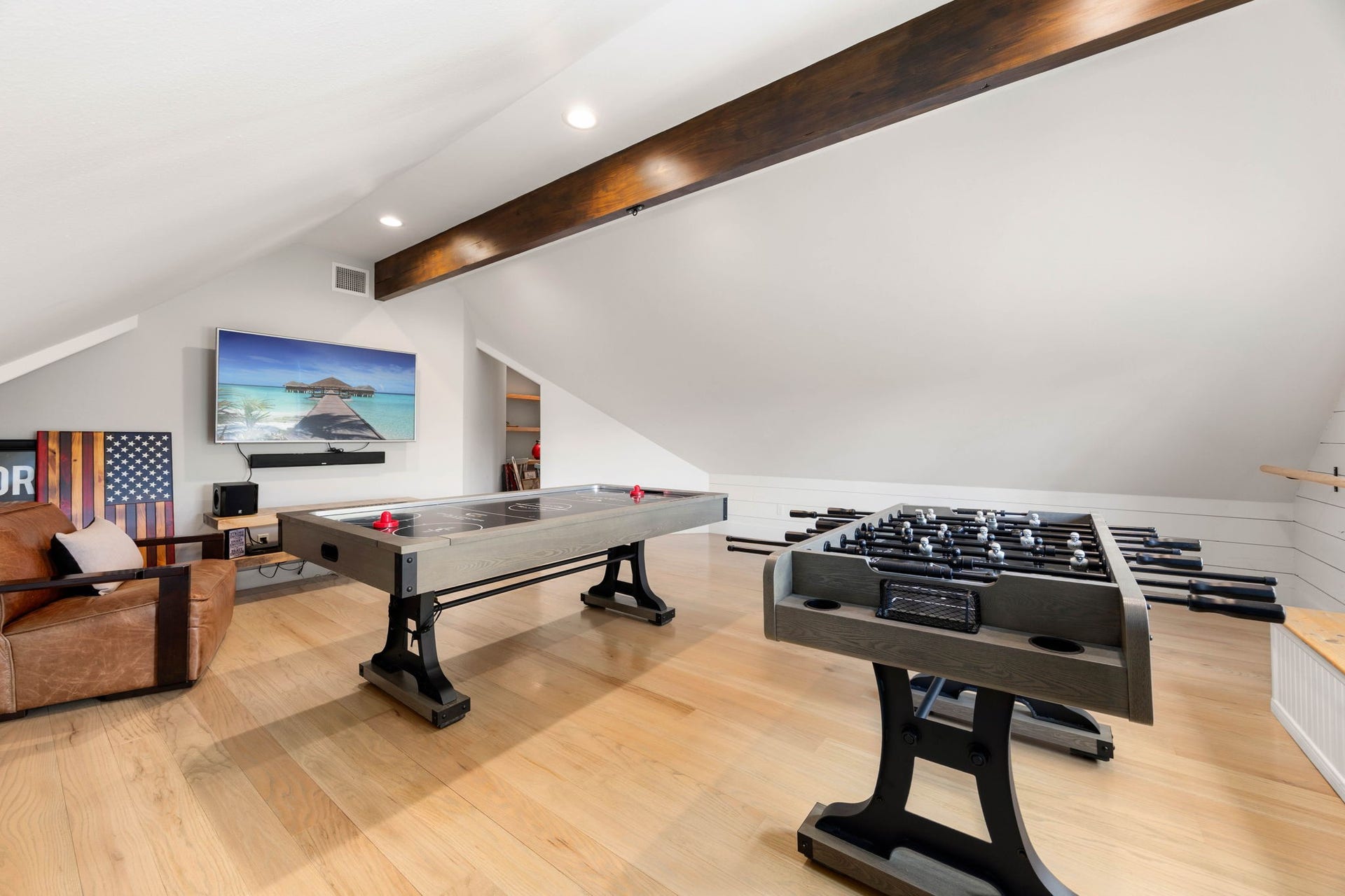 6571 Manorwood Drive, Katy, TX 77493 This expansive game room boasts a striking vaulted ceiling anchored by a heavy, dark-stained timber beam, creating an incredible space tailored for family fun and media entertainment. Whether it's hosting lively game nights, watching the big match, or just relaxing on the weekend, this versatile space is built for making unforgettable family memories.