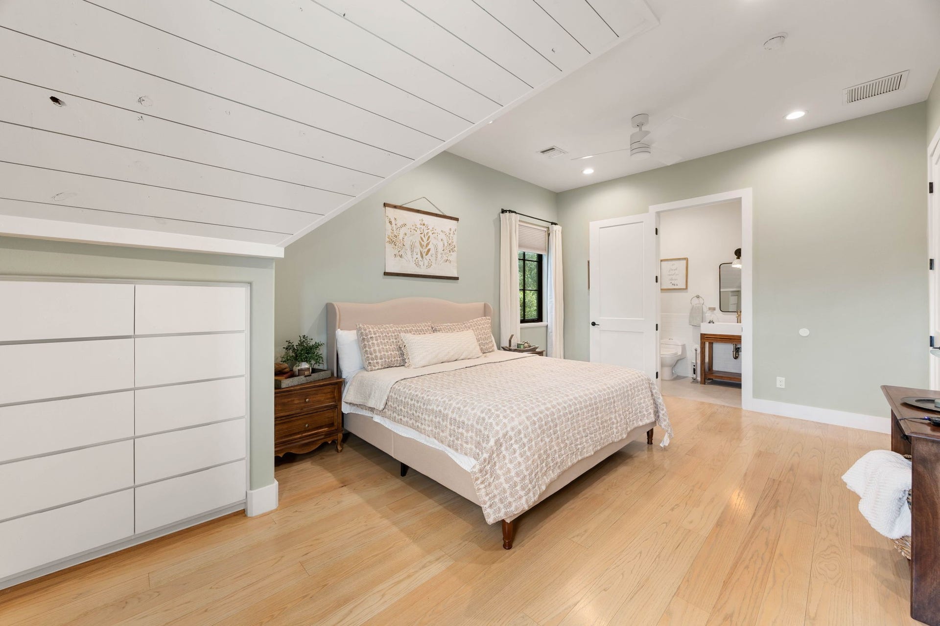 6571 Manorwood Drive, Katy, TX 77493 This spacious secondary bedroom highlights smart spatial planning with a large bank of custom built-in dresser drawers integrated seamlessly beneath a charming sloped shiplap plank ceiling.