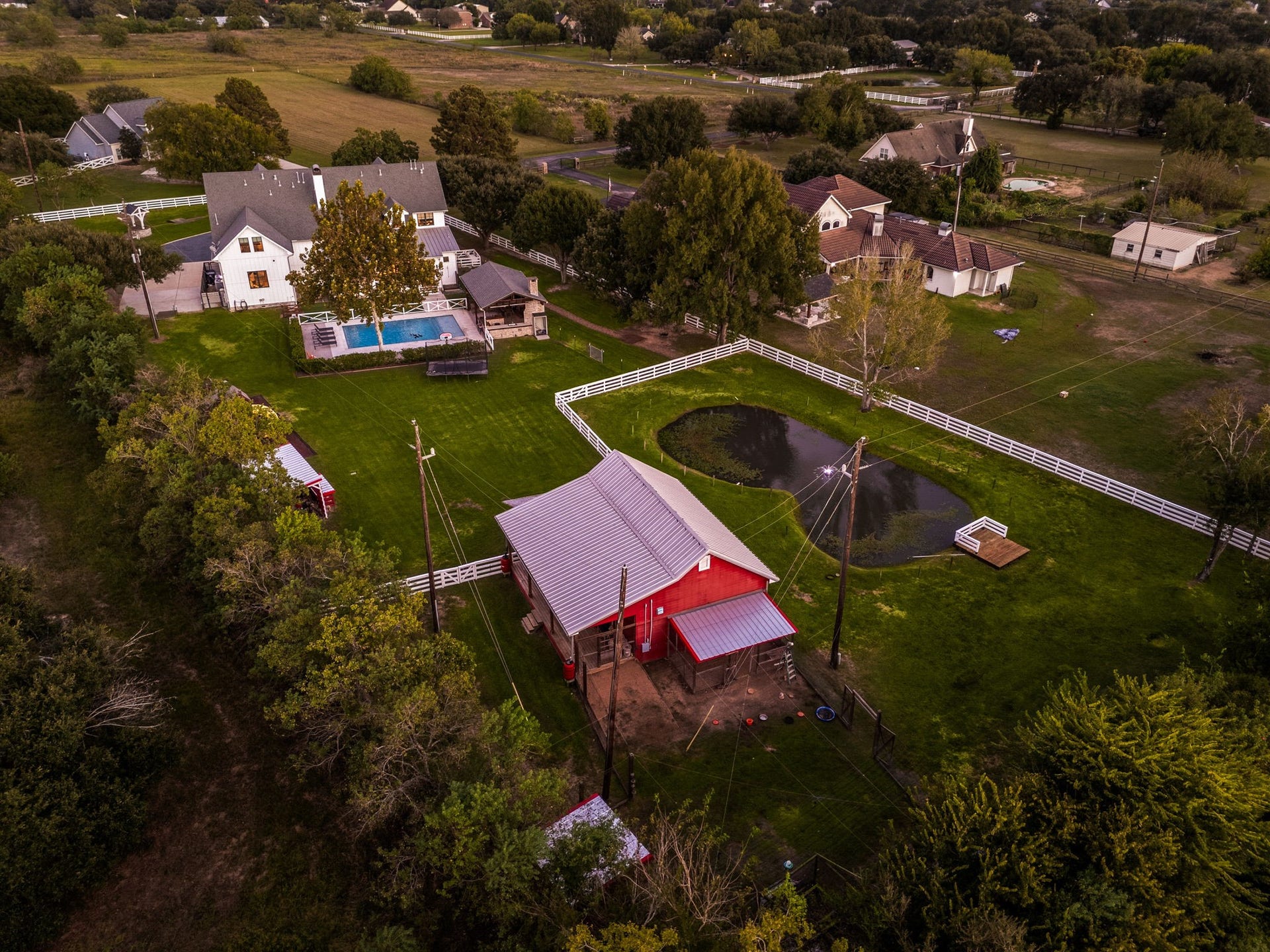 6571 Manorwood Drive, Katy, TX 77493 Experience the grand scale of this custom estate, highlighting how the main farmhouse, resort-style pool pavilion, private stocked pond, and red barn integrate across the sprawling acreage.