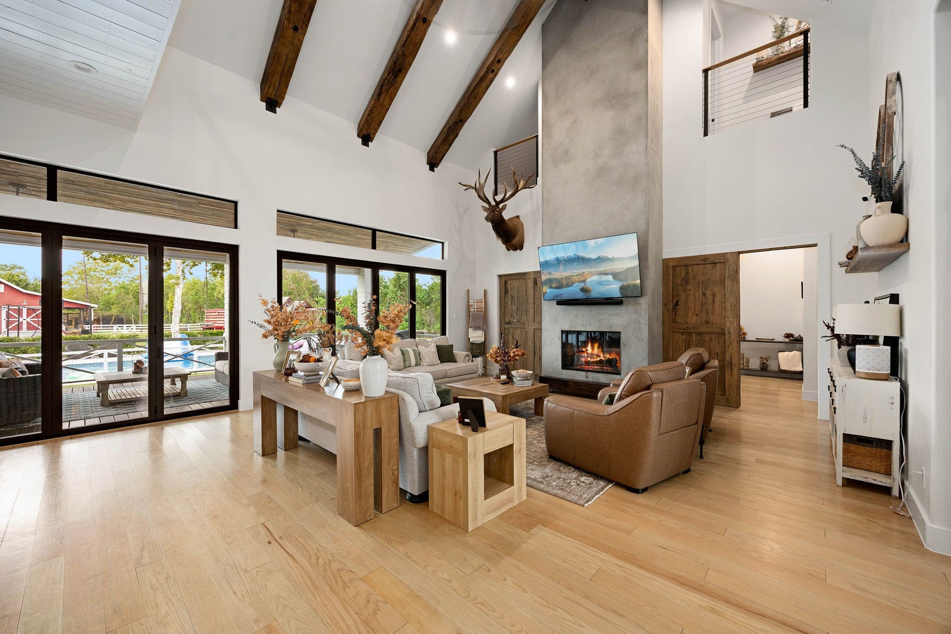 6571 Manorwood Drive, Katy, TX 77493 The magnificent living room boasts a dramatic cathedral ceiling anchored by massive exposed wood beams, gleaming wide-plank red oak wood flooring, and a stunning floor-to-ceiling concrete-finish fireplace surround.