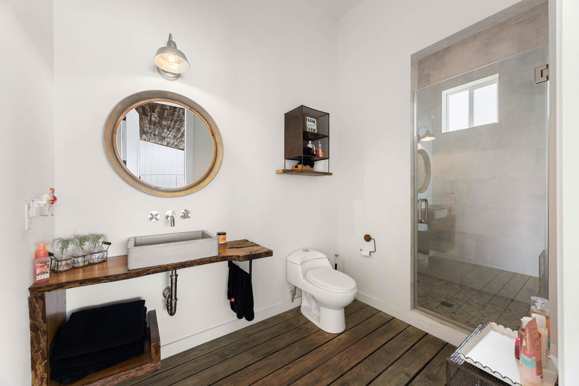 6571 Manorwood Drive, Katy, TX 77493 This spectacular full outdoor bathroom is designed perfectly for showering after a day in the sun, featuring durable wood-plank style flooring, crisp white walls, and an industrial-modern vanity mirror.