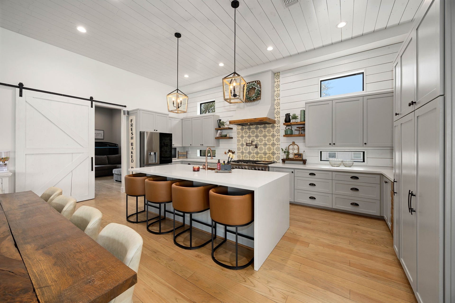 6571 Manorwood Drive, Katy, TX 77493 This gourmet culinary space features premium shaker-style cabinetry, custom quartz countertops, a sprawling center island with built-in microwave and breakfast bar seating, and a striking custom range hood accented with a natural wood beam header.