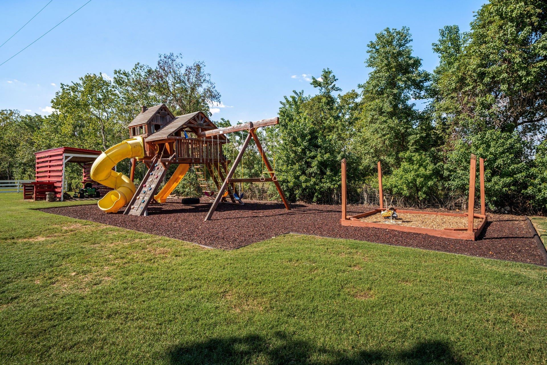 6571 Manorwood Drive, Katy, TX 77493 Perfectly complementing the estates expansive acreage, this dedicated children's play area features a premium, multi-level wooden playset with a climbing wall, spiral slide, and integrated swingsetall safely bordered with thick rubber mulch and flanked by an enclosed sandbox area.