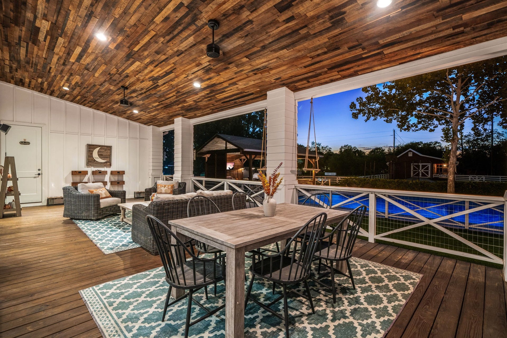 6571 Manorwood Drive, Katy, TX 77493 Step outside to the back covered patio. It features a breathtaking reclaimed wood plank ceiling equipped with recessed lighting and dual modern ceiling fans, all set over premium dark-stained wood decking. It is the absolute perfect spot to unwind at the end of the day, sip a cold drink, and enjoy the peaceful Texas breeze while watching the kids splash in the pool.