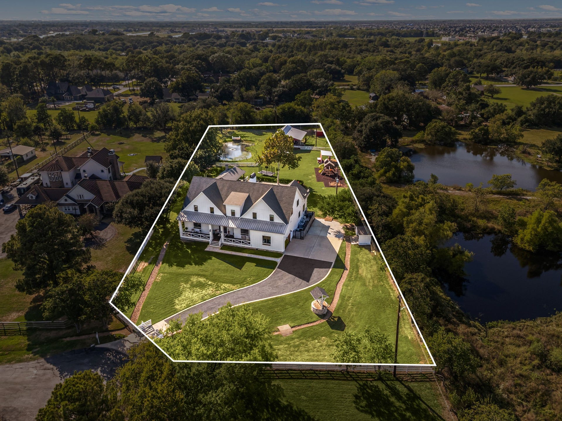 6571 Manorwood Drive, Katy, TX 77493 Welcome to the exceptional lifestyle offered by Manorwood Estates in Katy, where country elegance meets everyday convenience. Nestled on an expansive 1.7+ acre private tract, this magnificent modern farmhouse exemplifies the pinnacle of luxury estate living. A deep-set, manicured front lawn, a pool, outdoor kitchen, airconditioned barn with a gym, outdoor playground, garden w/sprinklers, and pond are just a few of the highlights of this magnificent property.