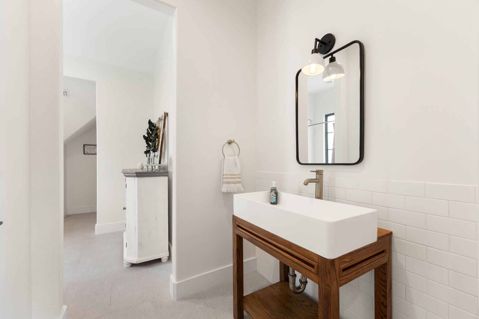 6571 Manorwood Drive, Katy, TX 77493 This secondary wash station features a matching custom open wood vanity console and a contemporary white vessel trough sink, perfectly mirroring the first vanity area on the opposite side of the layout.