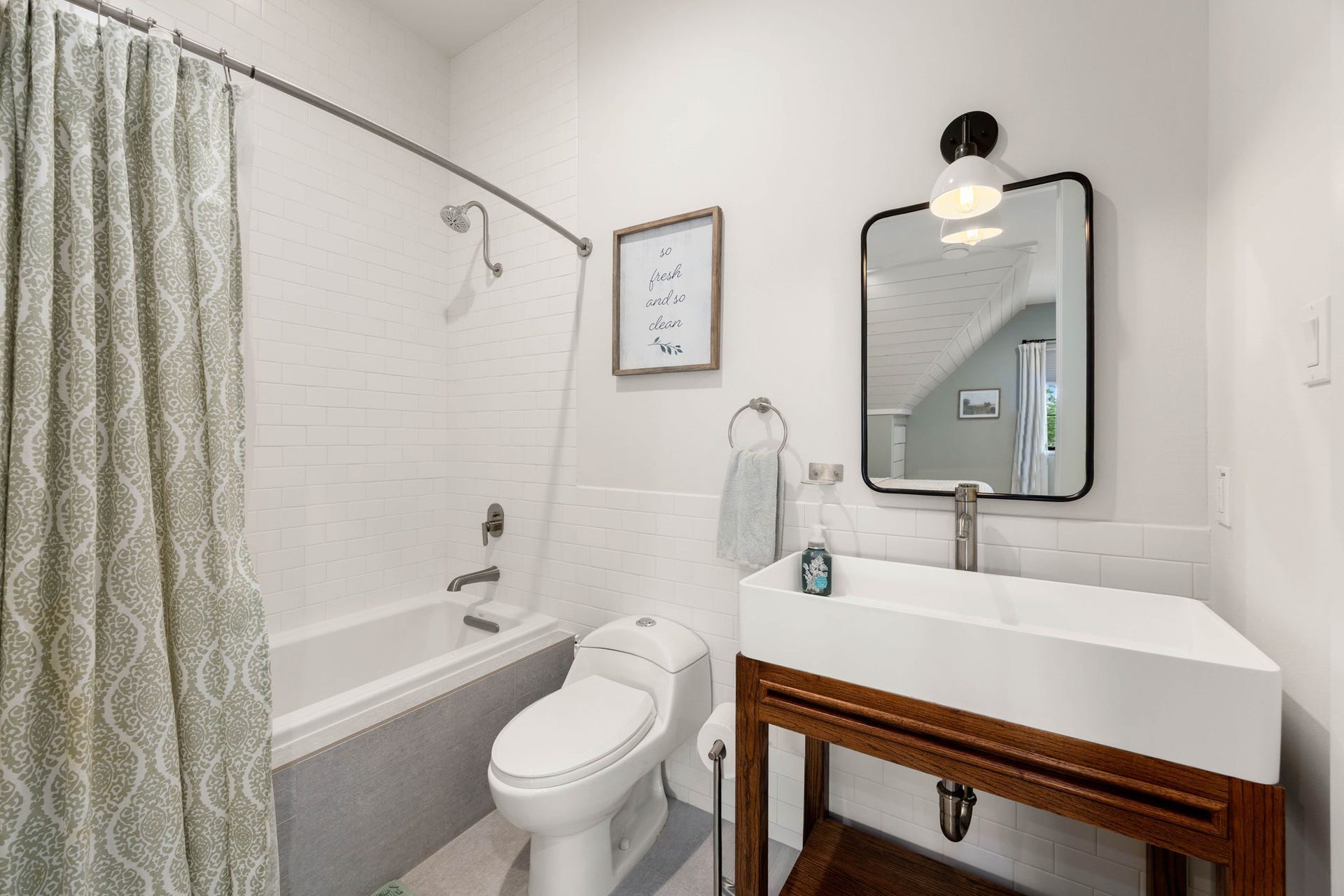 6571 Manorwood Drive, Katy, TX 77493 This full bathroom features a custom open wood vanity console supporting a contemporary white vessel trough sink with a sleek, high-arc brushed nickel faucet. Tucked quietly off the bedroom, it offers the perfect balance of daily convenience and secluded privacy for your family or overnight guests.