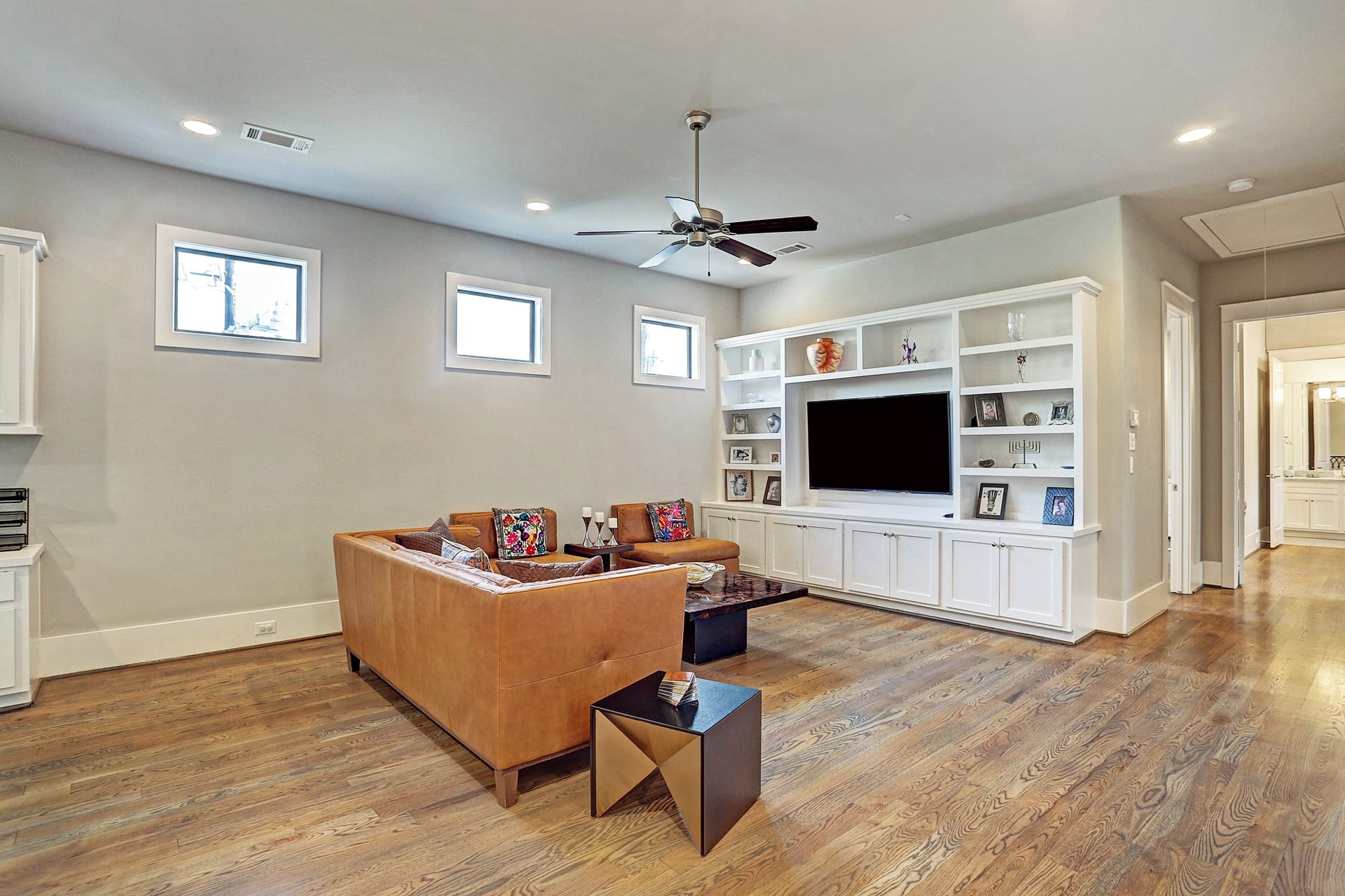16x19 game room on the second floor has built in entertainment center with shelves, ceiling fan, and recessed lighting.