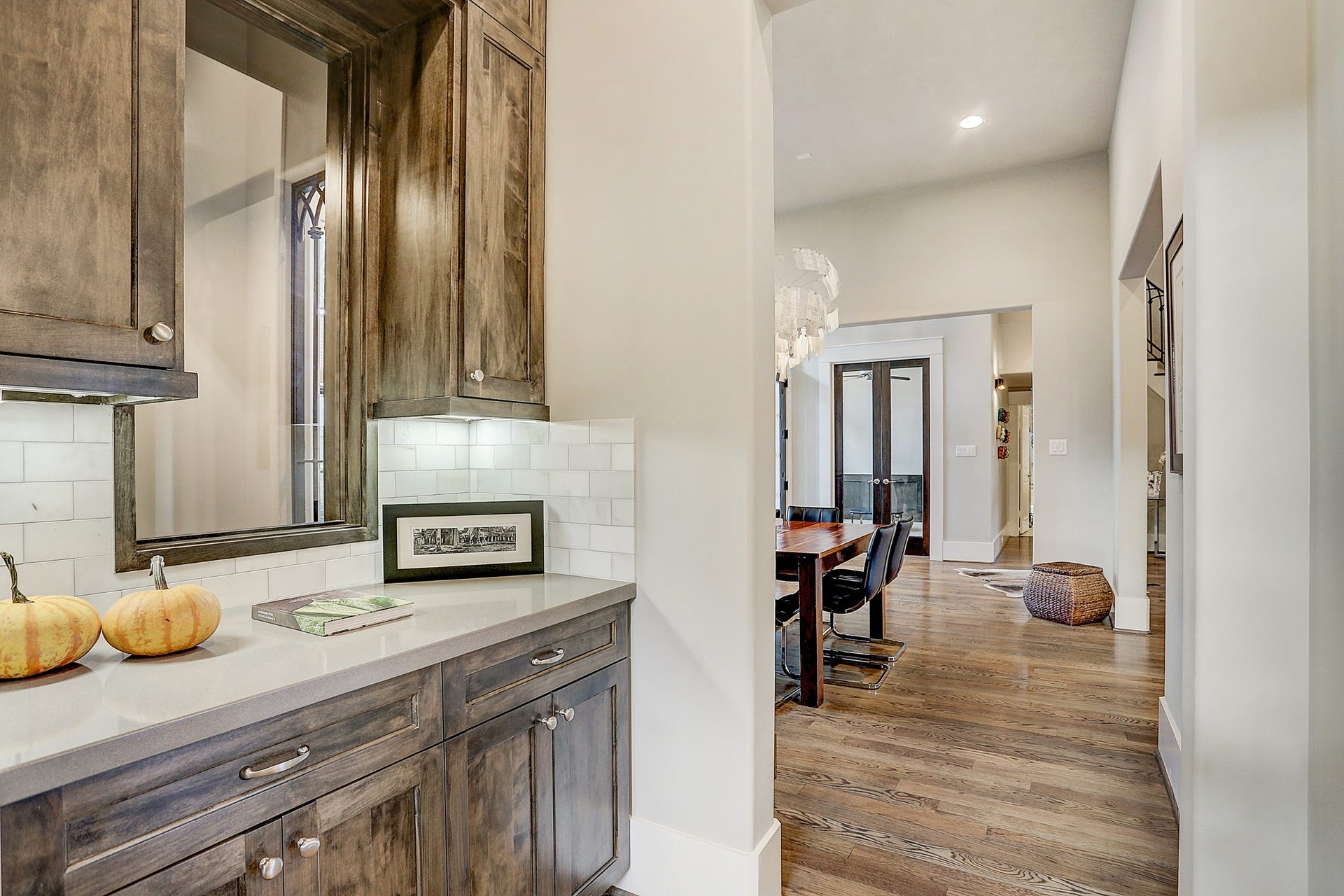 Butler pantry between the dining room and kitchen has quartz counter, Carrara marble subway tile backsplash, and under cabinet lighting.