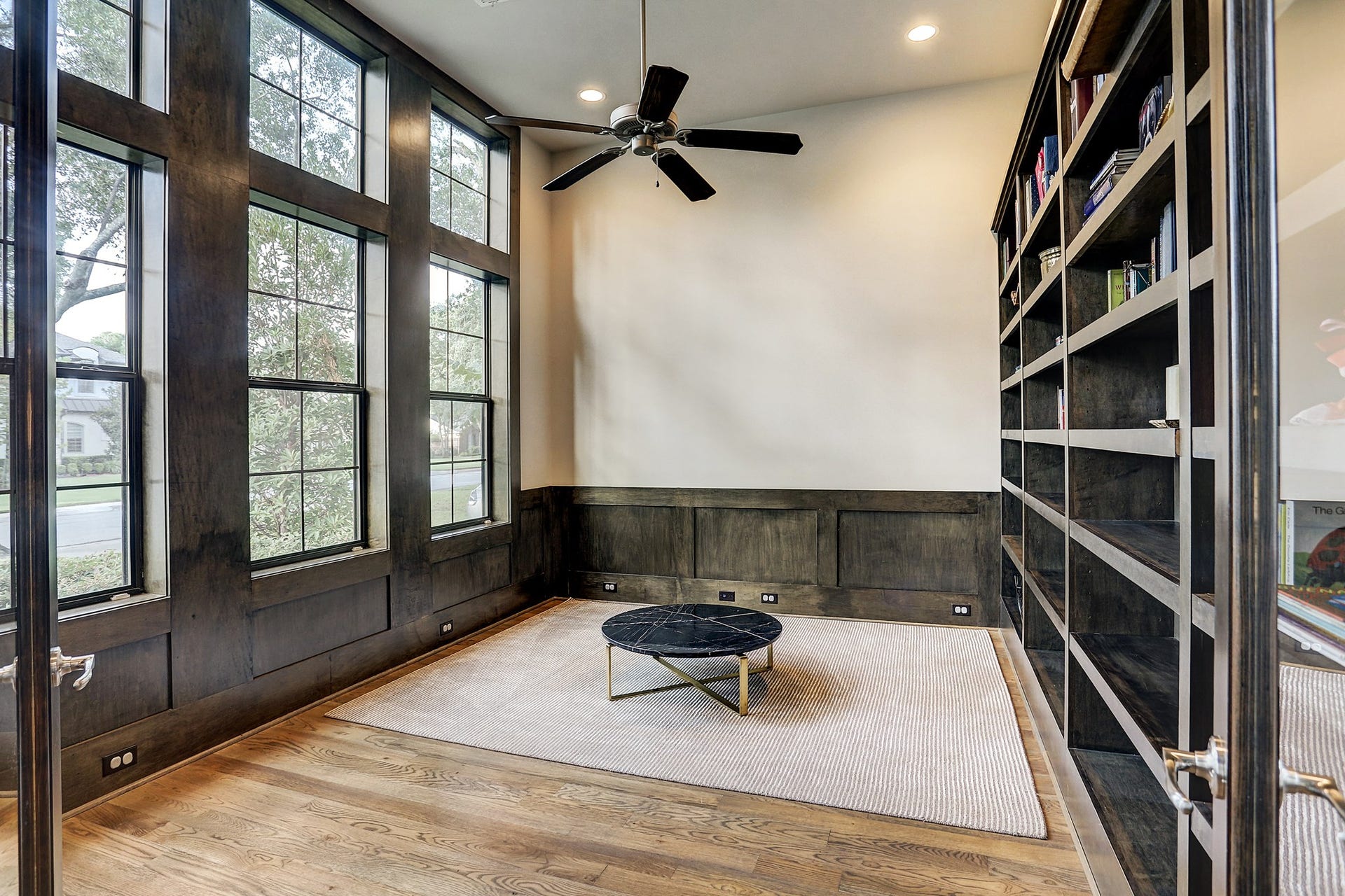 10x15 1st floor study has large windows, floor-to-ceiling built in shelves, ceiling fan, and recessed lighting.