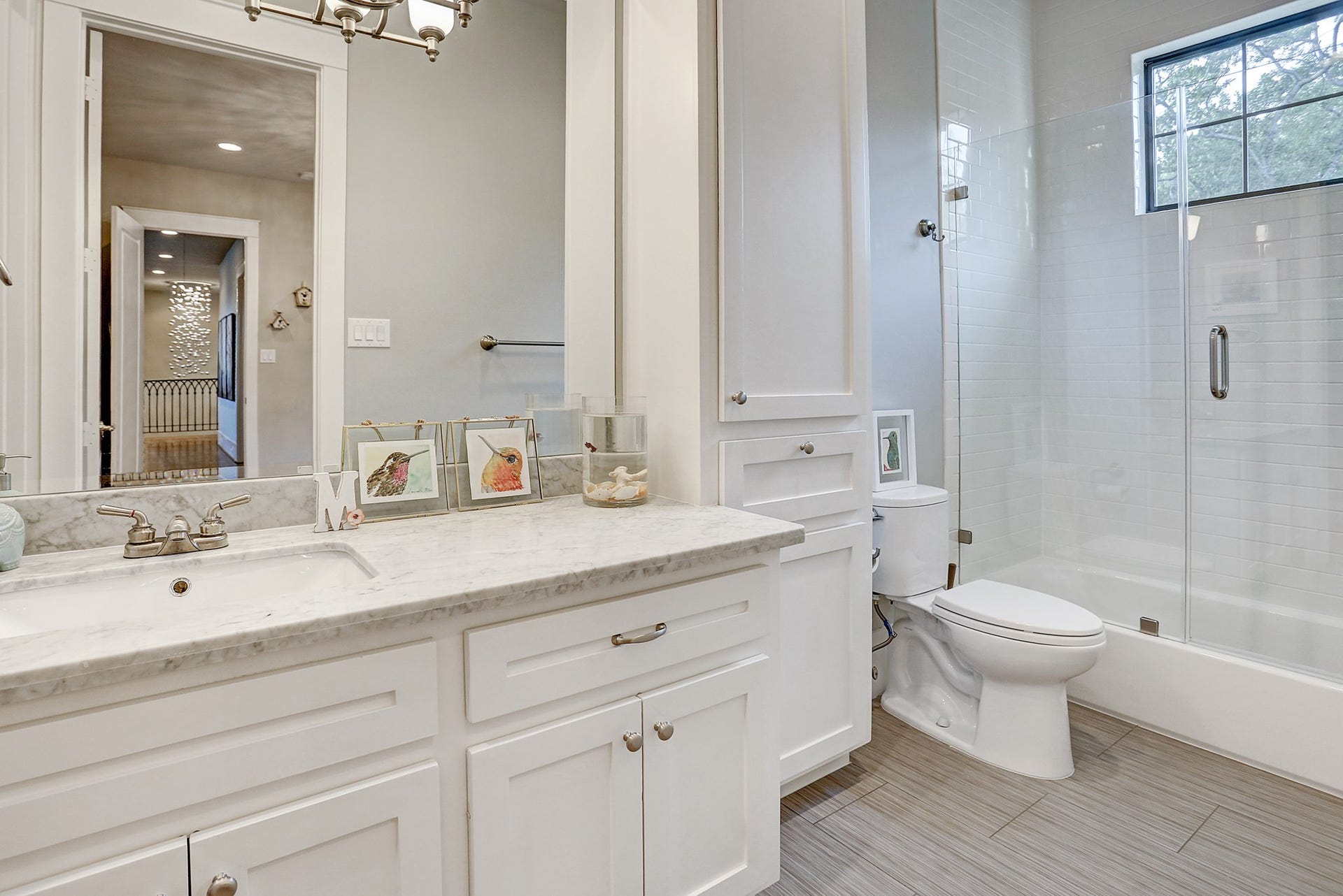 Ensuite bathroom for 3rd bedroom has tile floor, tub/shower combo with subway tile surround, Carrara marble counter, and custom lighting.