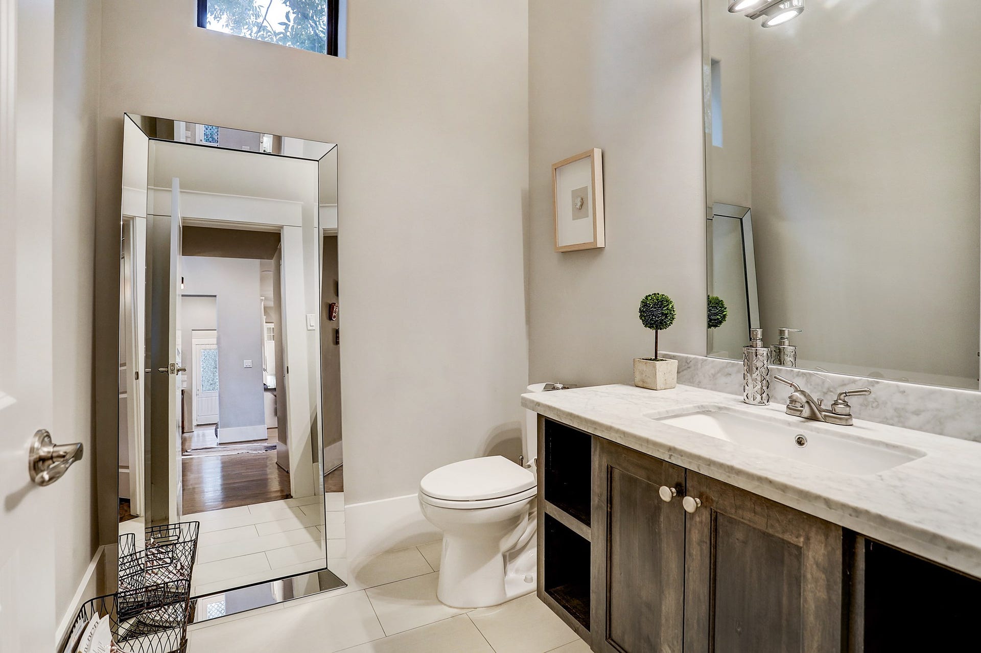First floor powder bath has tile floor, Carrara marble counter, and custom lighting.