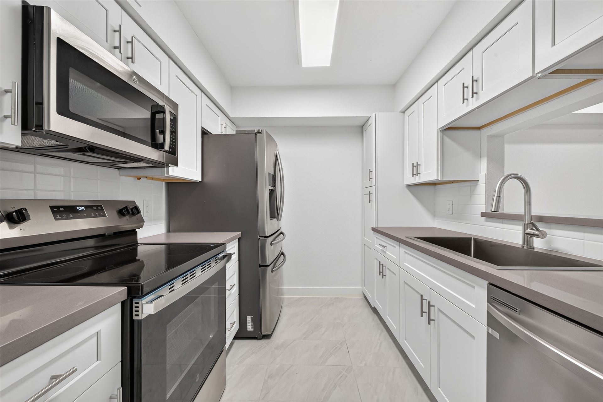 4633 Wild Indigo Street, #530, Houston, TX 77027 Beautifully redesigned kitchen showcasing Concrete Grey quartz countertops, white shaker cabinetry, brushed nickel hardware, and stainless steel appliances.