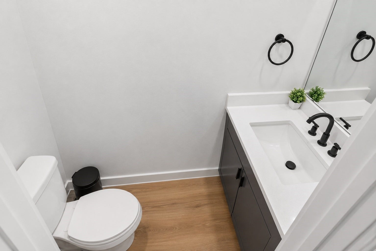 Conveniently located powder room continues the homes cohesive design with quartz countertops, contemporary cabinetry, matte black fixtures, and clean architectural lines. Positioned just off the main living area, it provides both style and convenience when entertaining guests.