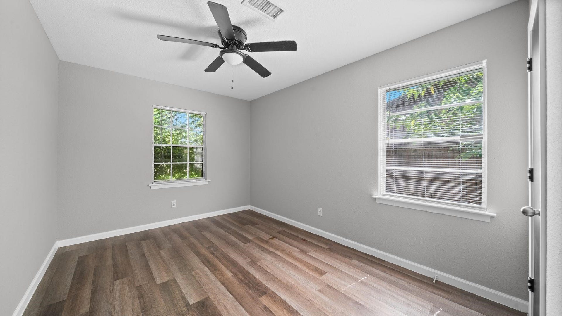 5242 Greylog Drive, Houston, TX 77048 This well-appointed secondary bedroom features luxury vinyl flooring, two windows with blinds that welcome natural light, and a ceiling fan with integrated lighting. A spacious walk-in closet provides ample storage, completing this comfortable and inviting retreat.