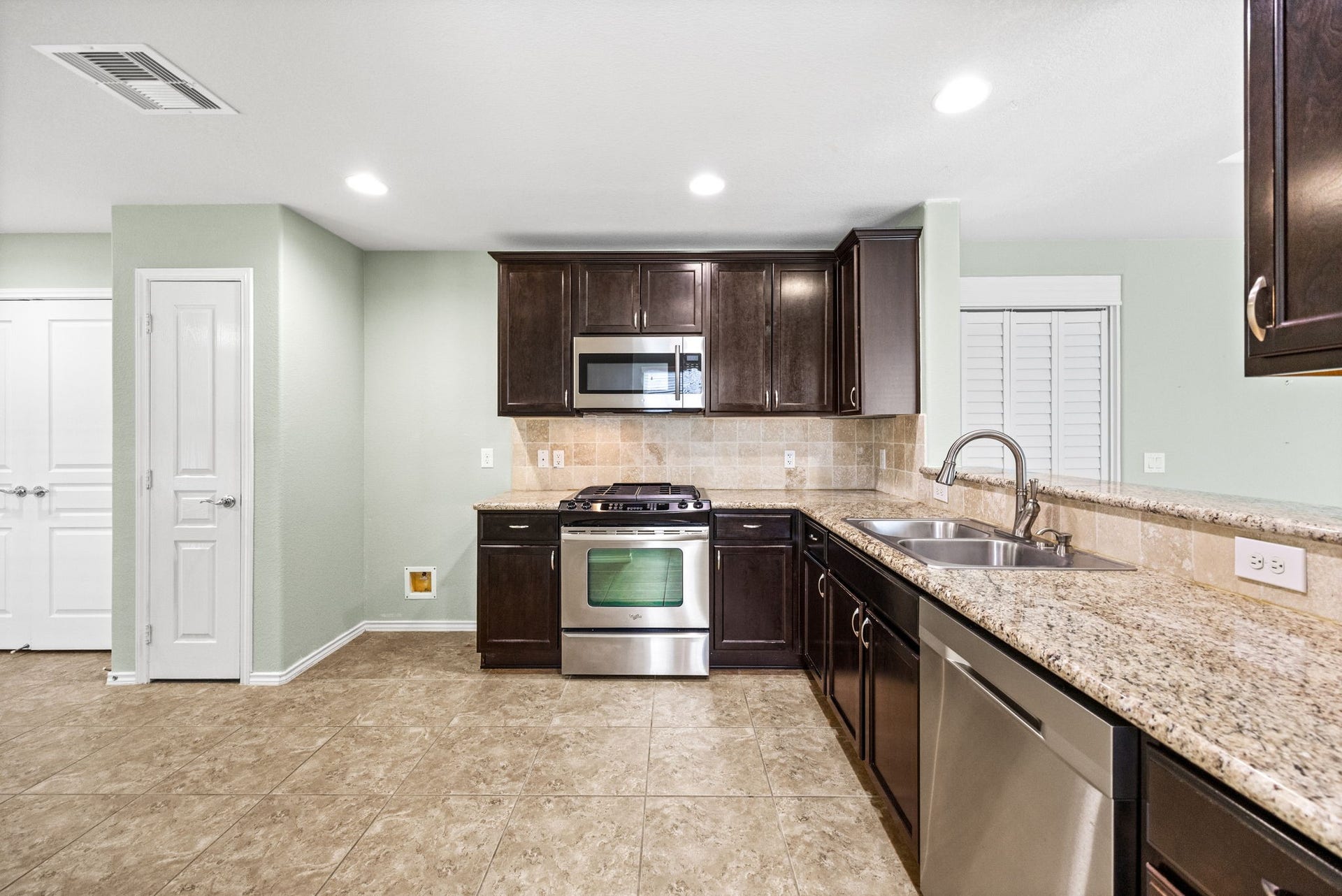 Kitchen features rich dark color cabinets, stainless steel appliances and lovely granite counter tops.