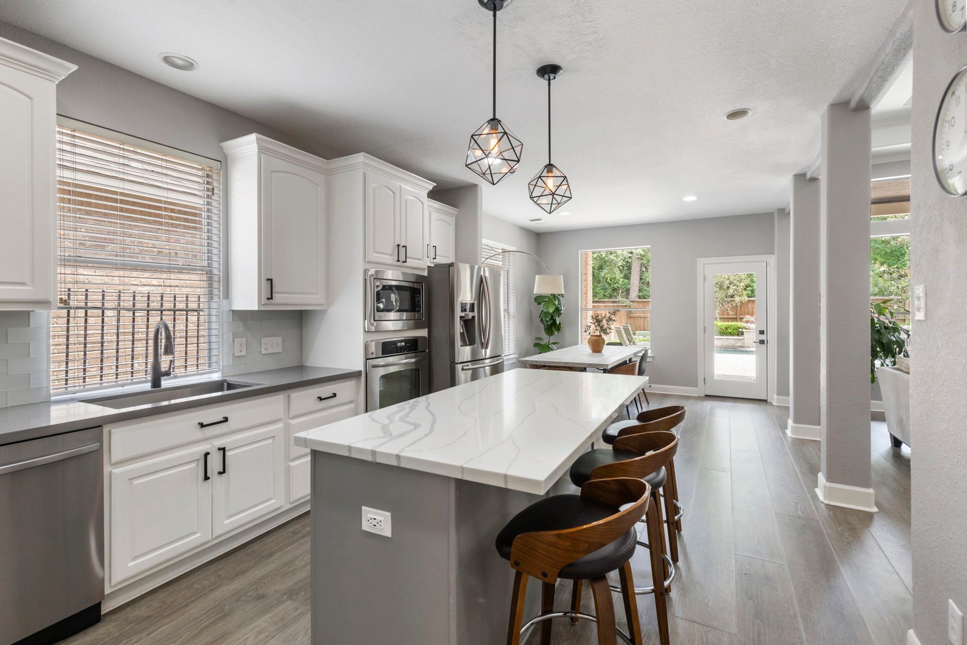 130 S Arrow Canyon Circle, The Woodlands, TX 77389 Modern kitchen with sleek white cabinetry, stainless steel appliances, and a spacious island. Pendant lighting adds elegance. Perfect for entertaining.