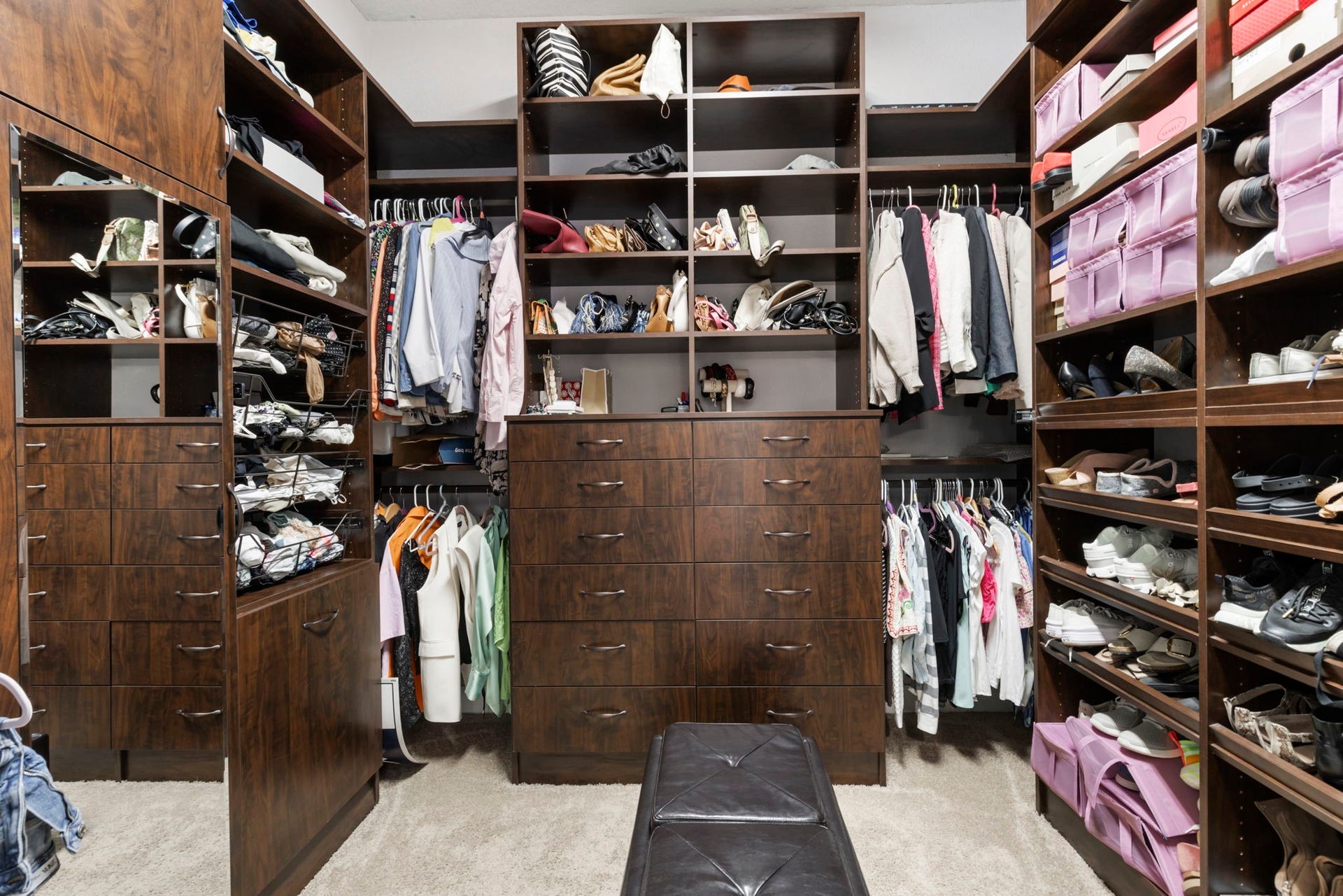 130 S Arrow Canyon Circle, The Woodlands, TX 77389 This spacious walk-in closet features rich wood cabinetry with ample shelving, hanging space, and drawers. It offers organized storage for clothing, shoes, and accessories.