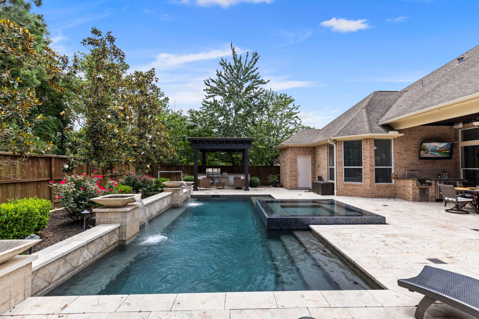 130 S Arrow Canyon Circle, The Woodlands, TX 77389 Beautiful backyard with a luxurious pool and spa, surrounded by lush landscaping and a wooden privacy fence, with no back neighbors!
