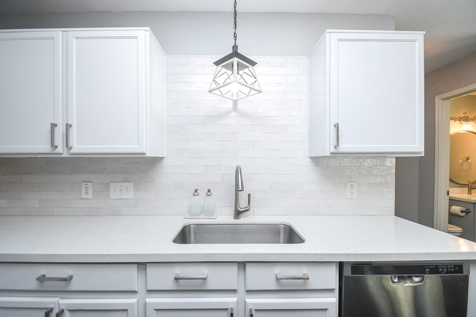 10222 Antelope Alley, Missouri City, TX 77459 Sleek kitchen with modern white cabinetry, a stylish backsplash, and stainless steel appliances, highlighted by elegant pendant lighting above the sink.