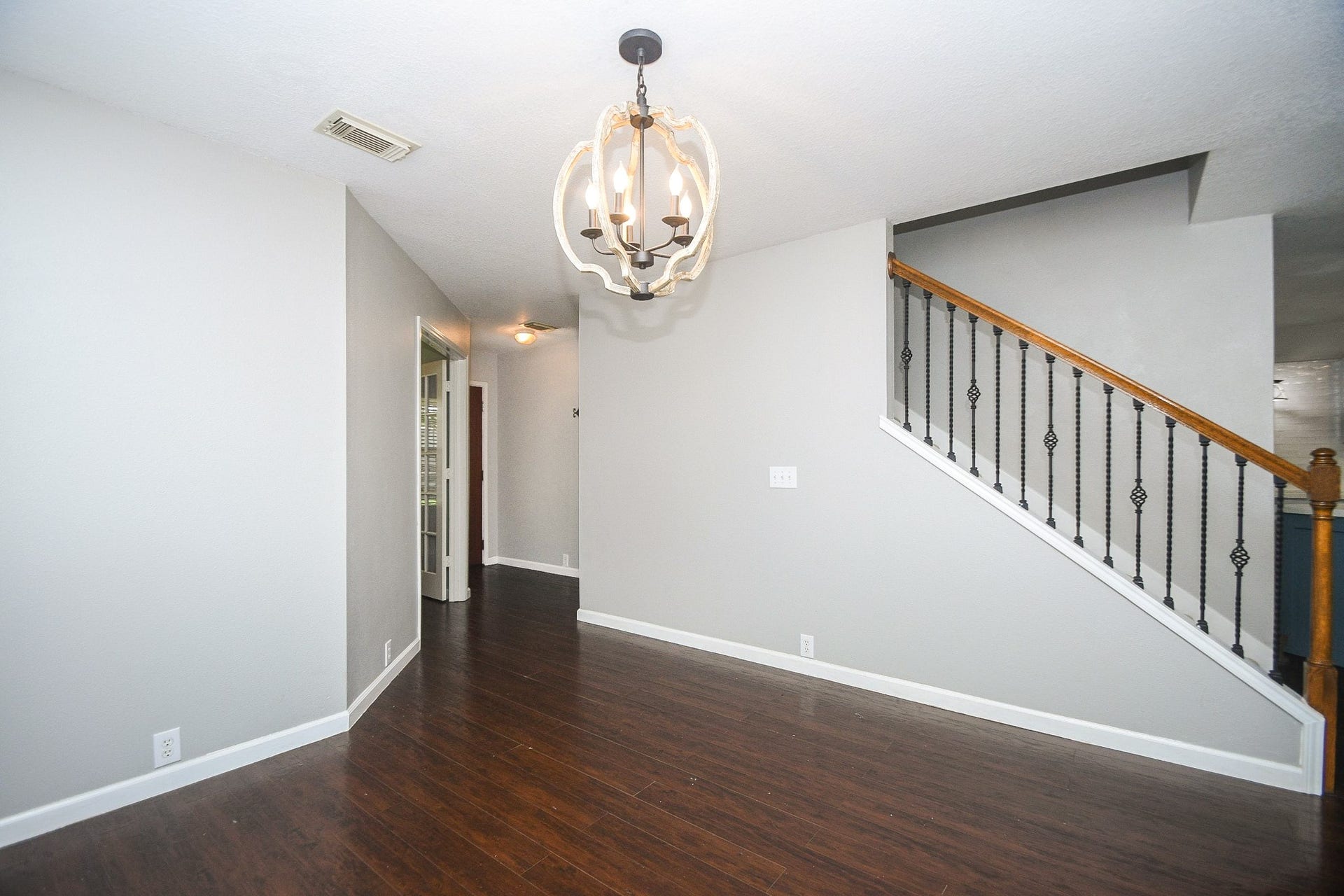 10222 Antelope Alley, Missouri City, TX 77459 Bright and inviting hallway with elegant dark wood flooring, modern light fixture, and stylish staircase with wrought iron details.