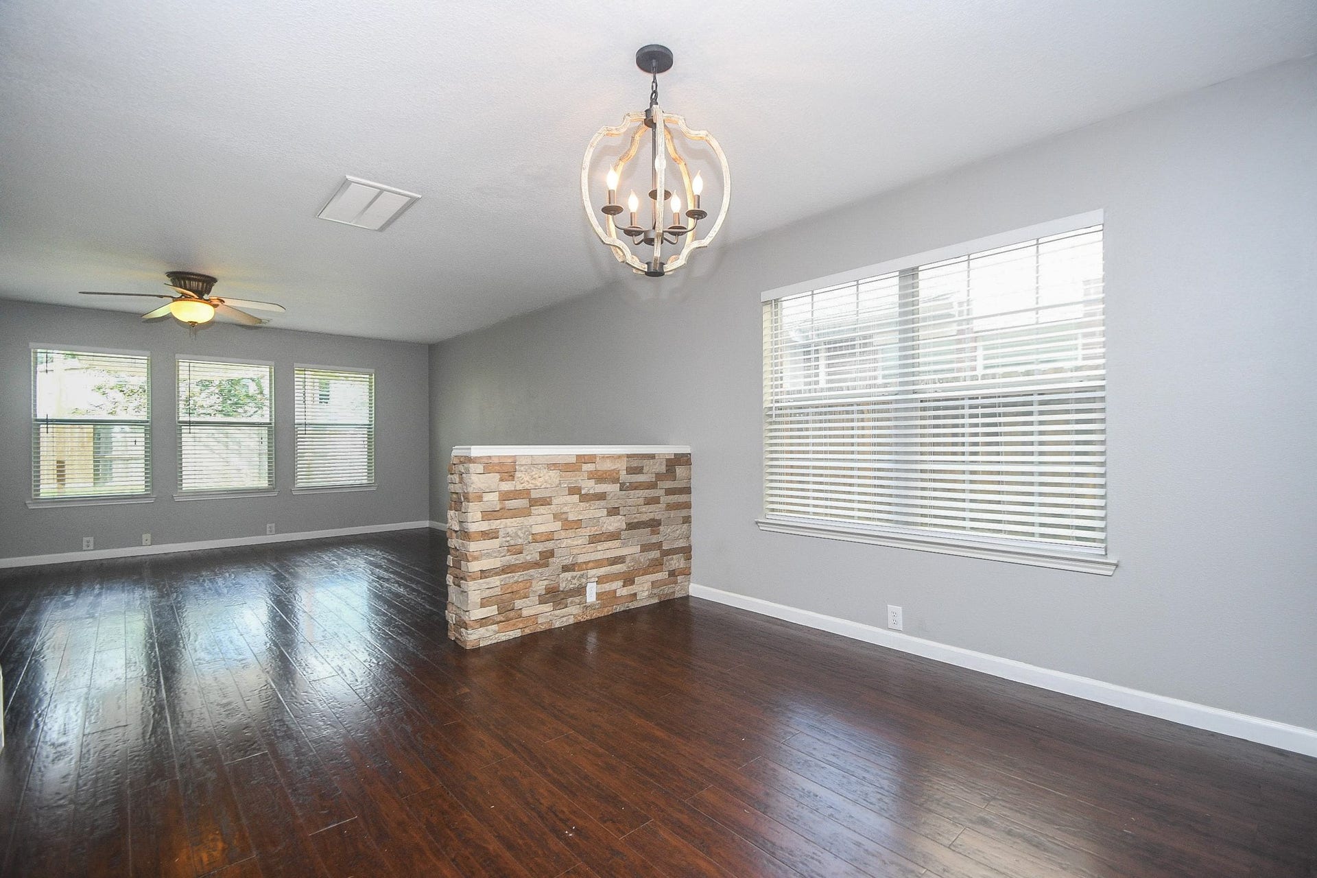10222 Antelope Alley, Missouri City, TX 77459 Spacious living area with rich laminate hardwood floors, large windows for natural light, and a stylish stone accent wall.